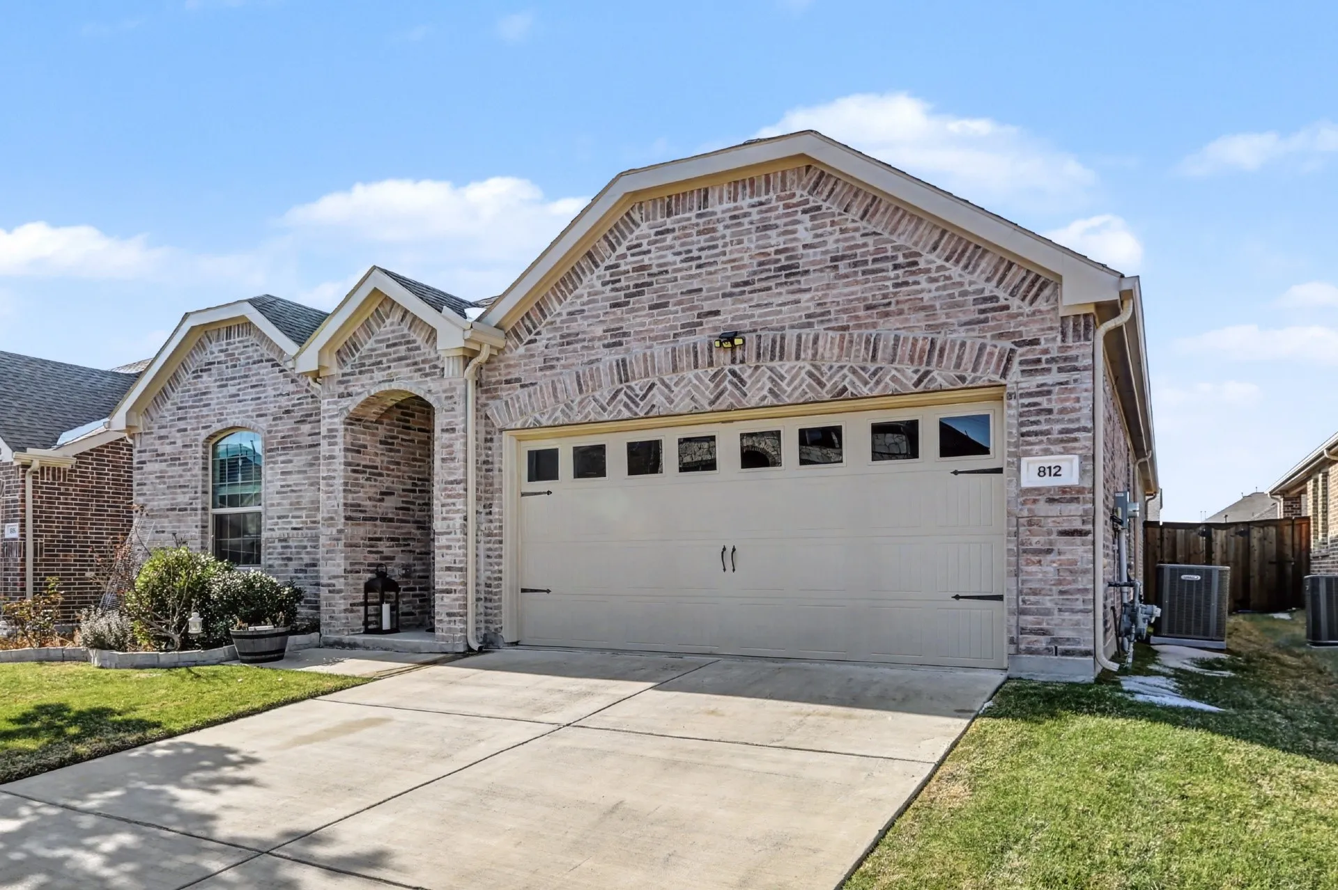 Brick exterior featuring gabled rooflines, an arched entry, and a two-car garage with decorative hardware