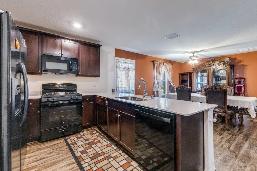 Kitchen featuring wood-finish flooring, dark wood cabinetry, and light countertops