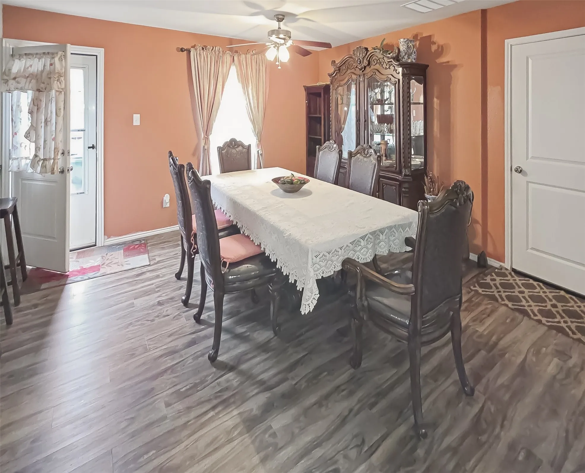 Wood-finish flooring throughout, ceiling fan with light fixture, and a white paneled door