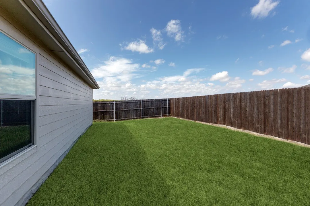 Expansive backyard featuring a manicured lawn, full privacy fencing, and horizontal siding