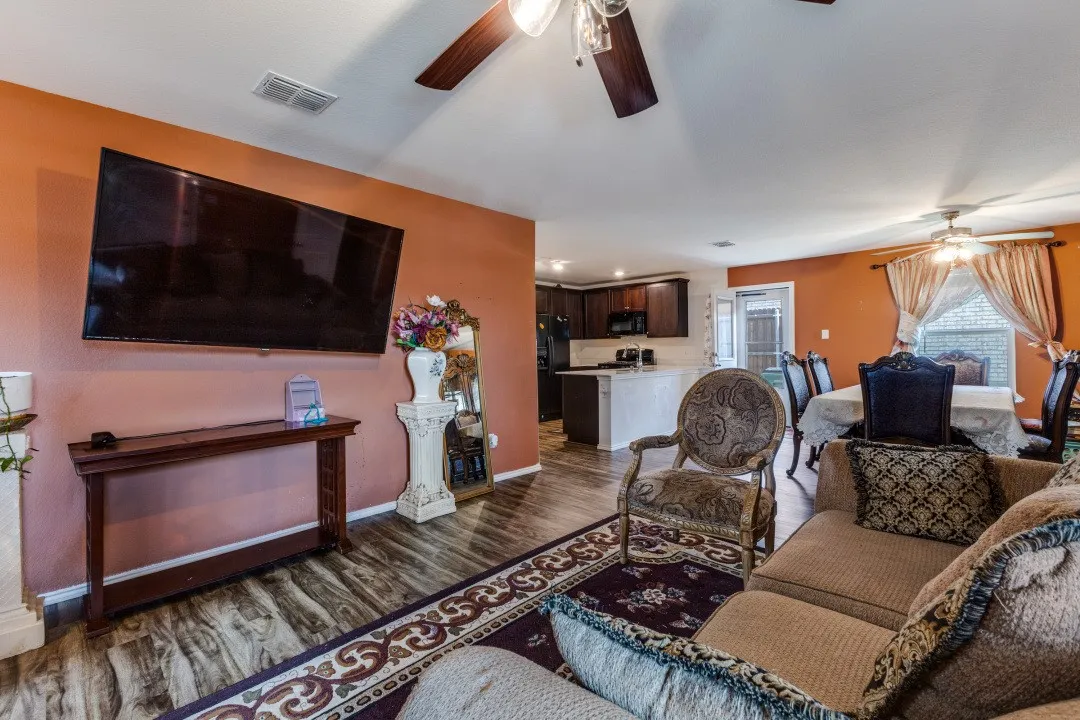 Open concept living area featuring wood-finish flooring, a ceiling fan, and a kitchen with dark wood cabinetry and a white countertop