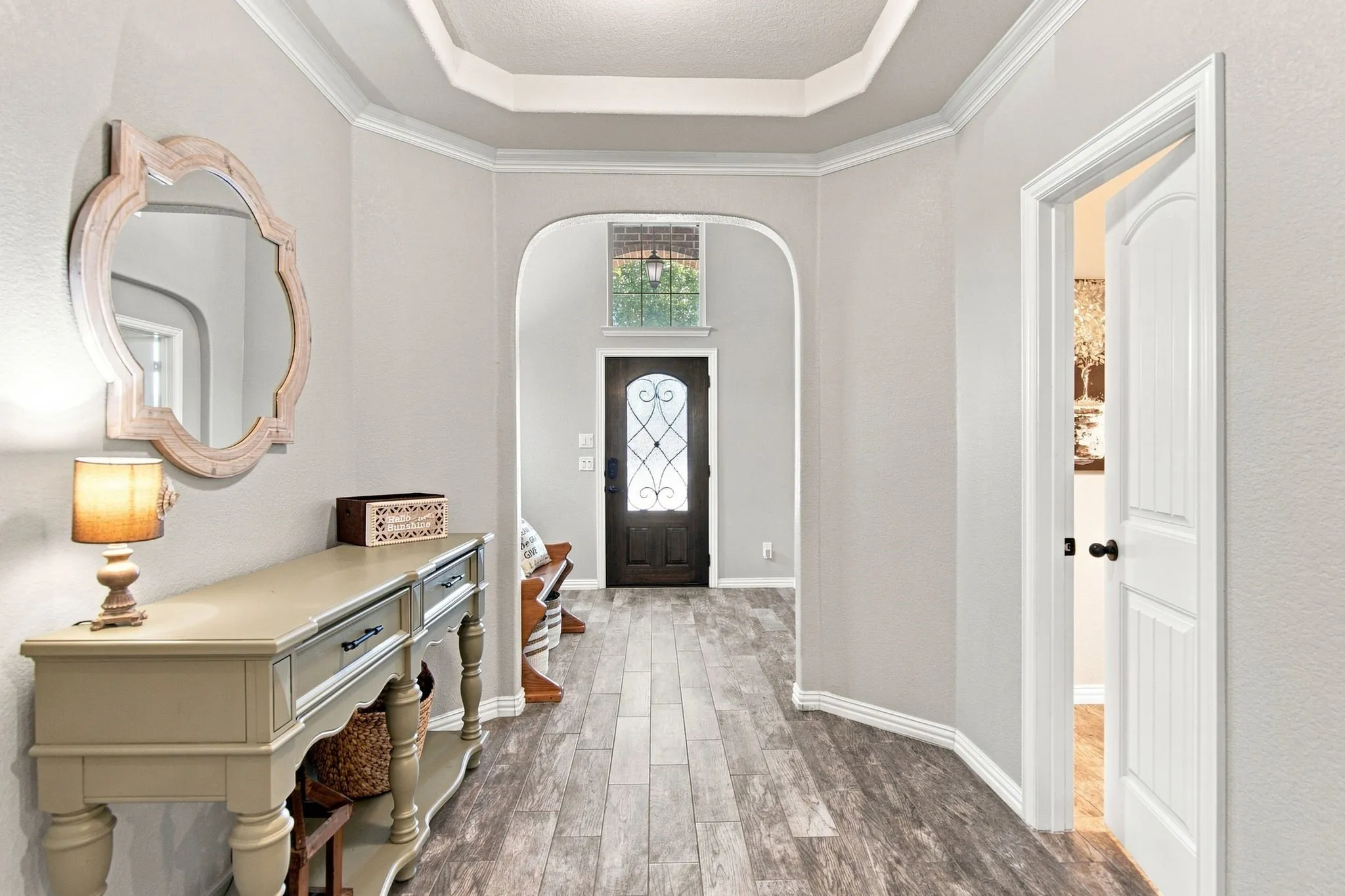 Gorgeous view throughout the home front every spot.  Powder bath on the right.  Wood look tile through the entry and living, dining, kitchen.  Tiered ceiling with trim make this area a standout!