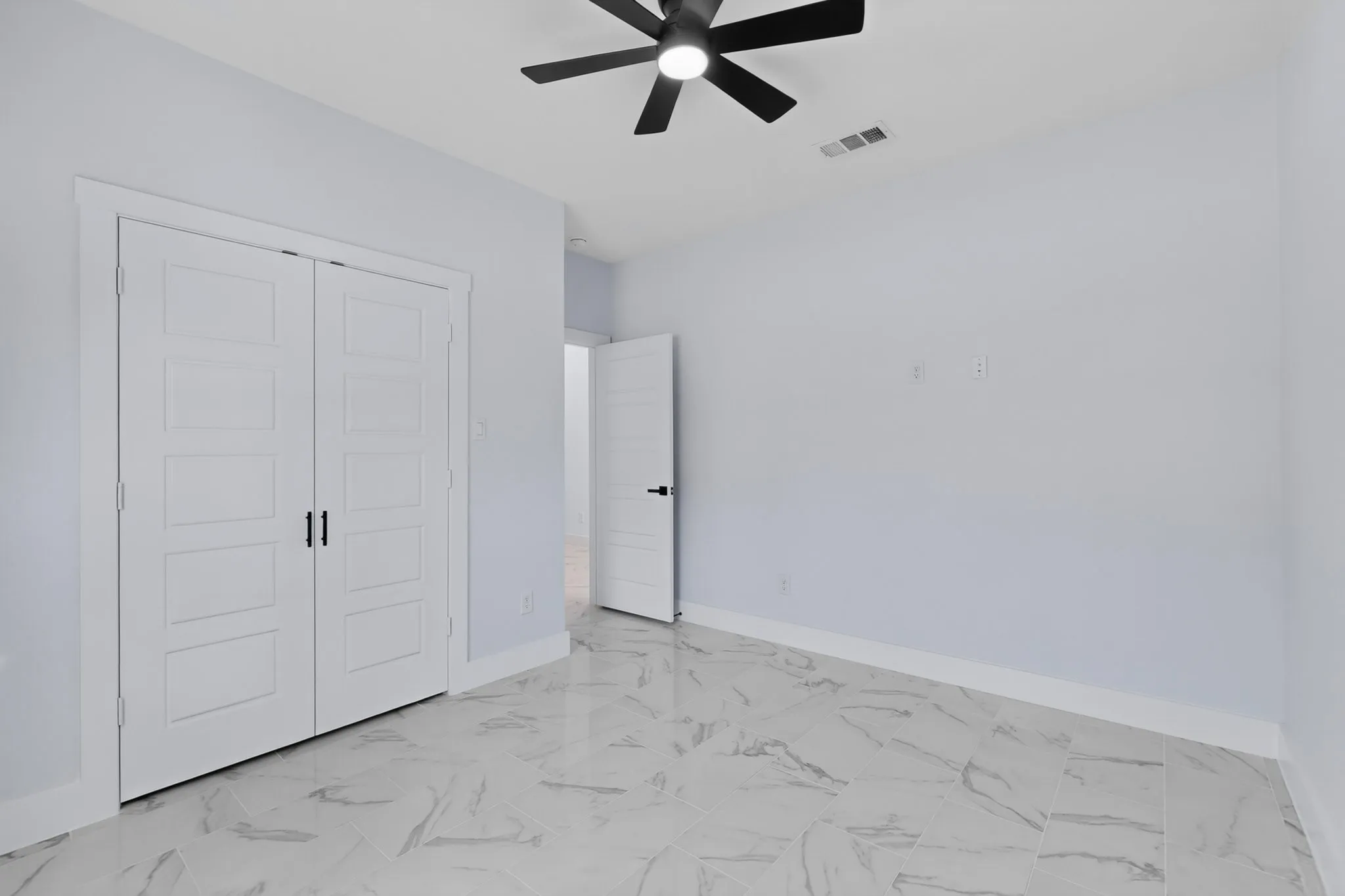 White walls with sleek white trim, a black ceiling fan, and white doors with matte black hardware