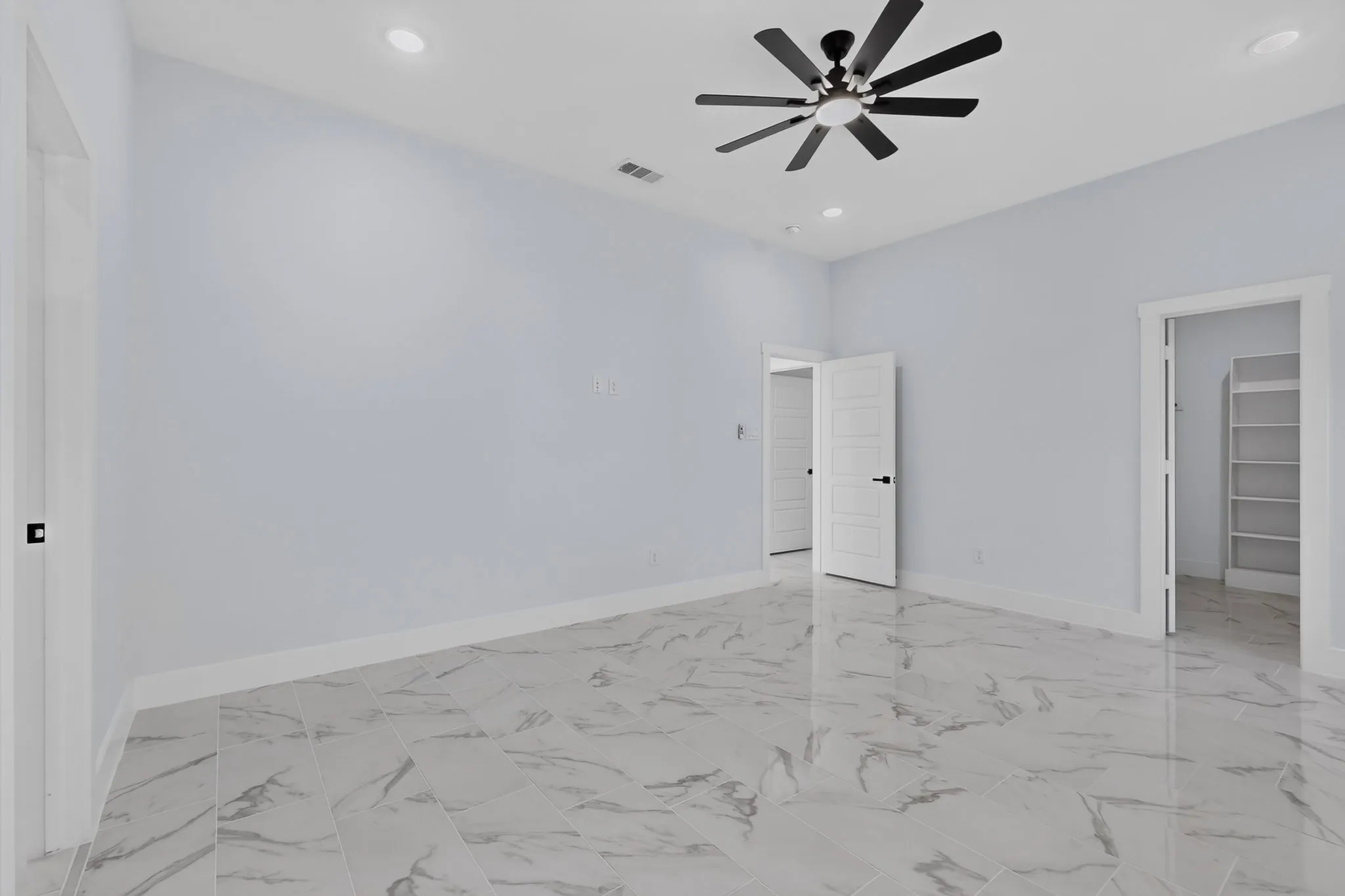 Recessed lighting, ceiling fan with black blades, and marble-finish flooring