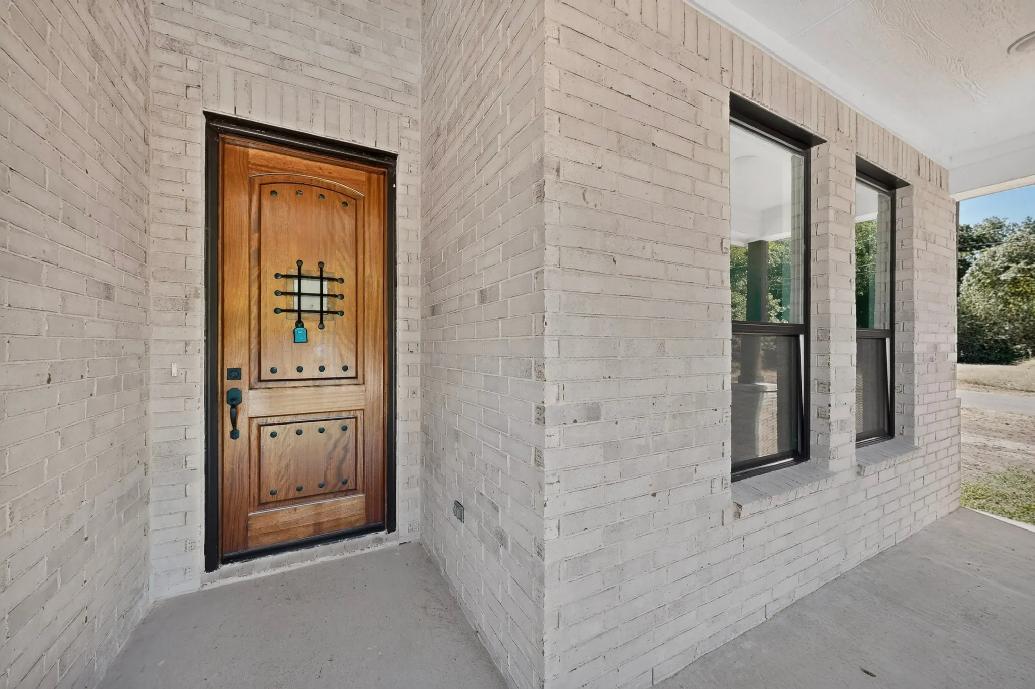 Whitewashed brick exterior with a wood-panel entry door featuring decorative metalwork