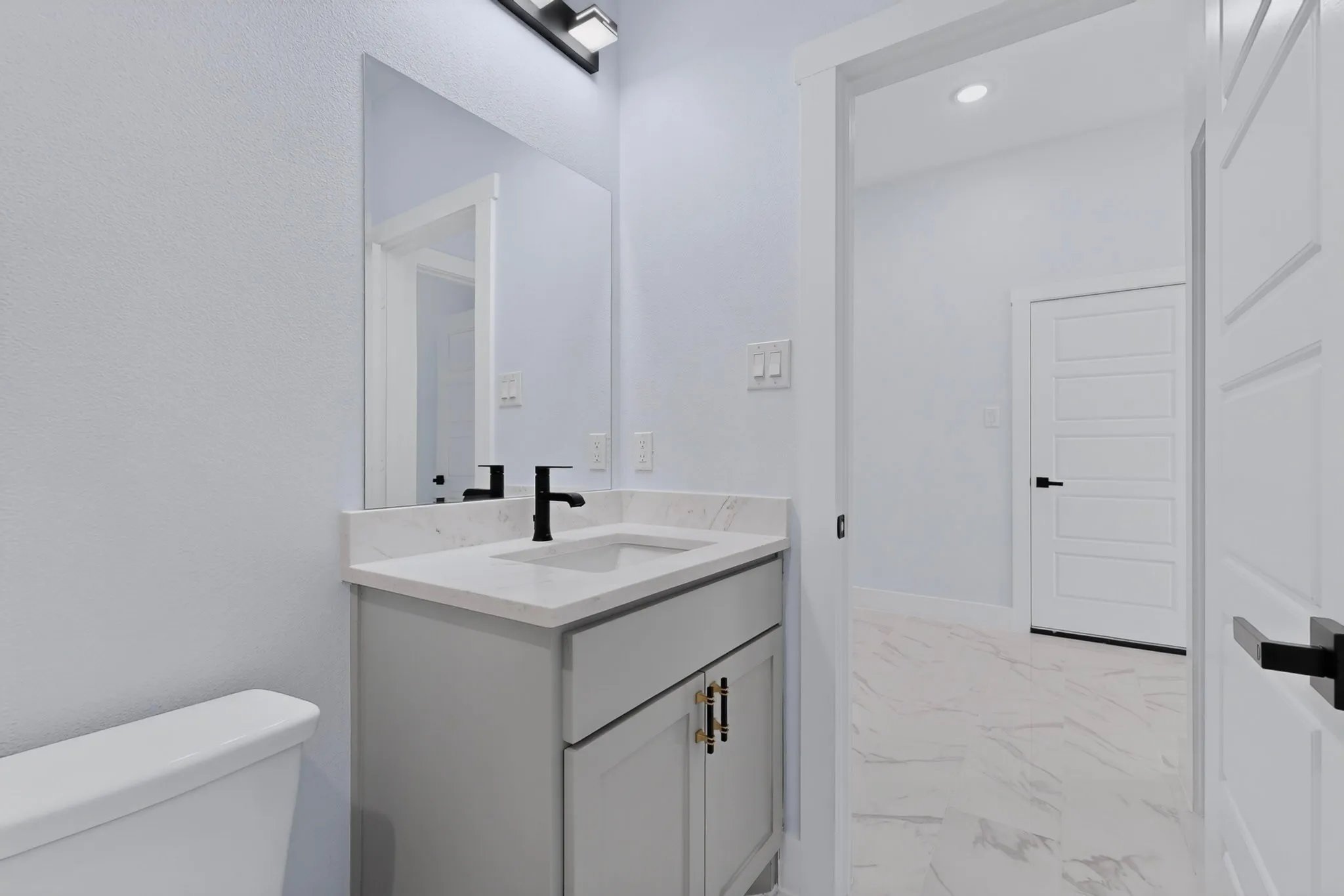Bathroom featuring a modern vanity with light gray cabinetry, white countertop, and matte black faucet