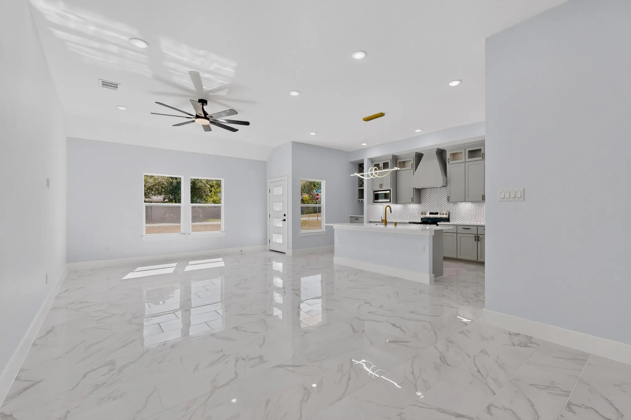 Open concept living space featuring polished tile flooring, recessed lighting, a ceiling fan, and a kitchen with an island and pendant lighting