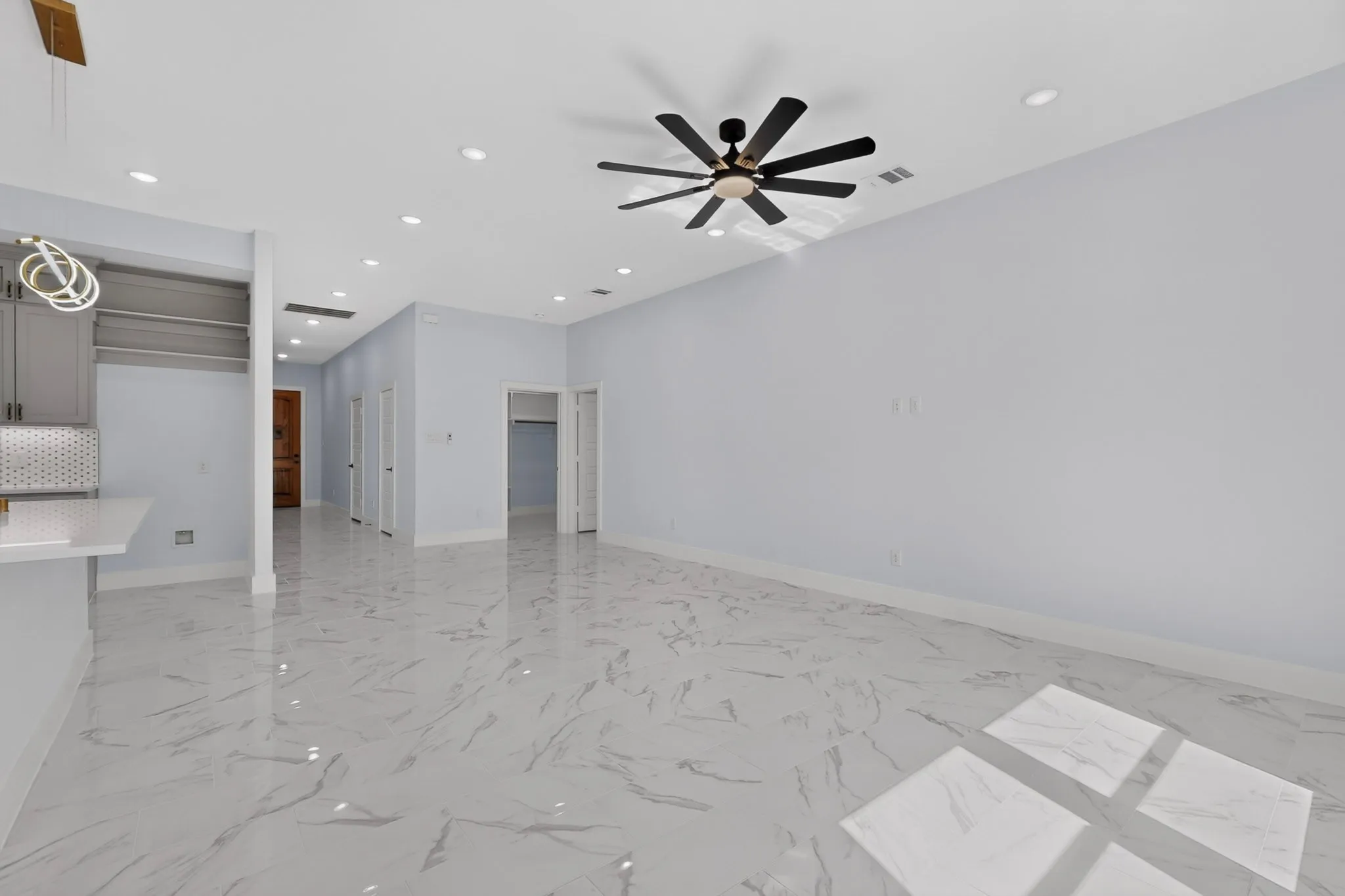 Spacious room with large format tile flooring, recessed lighting, and a contemporary ceiling fan