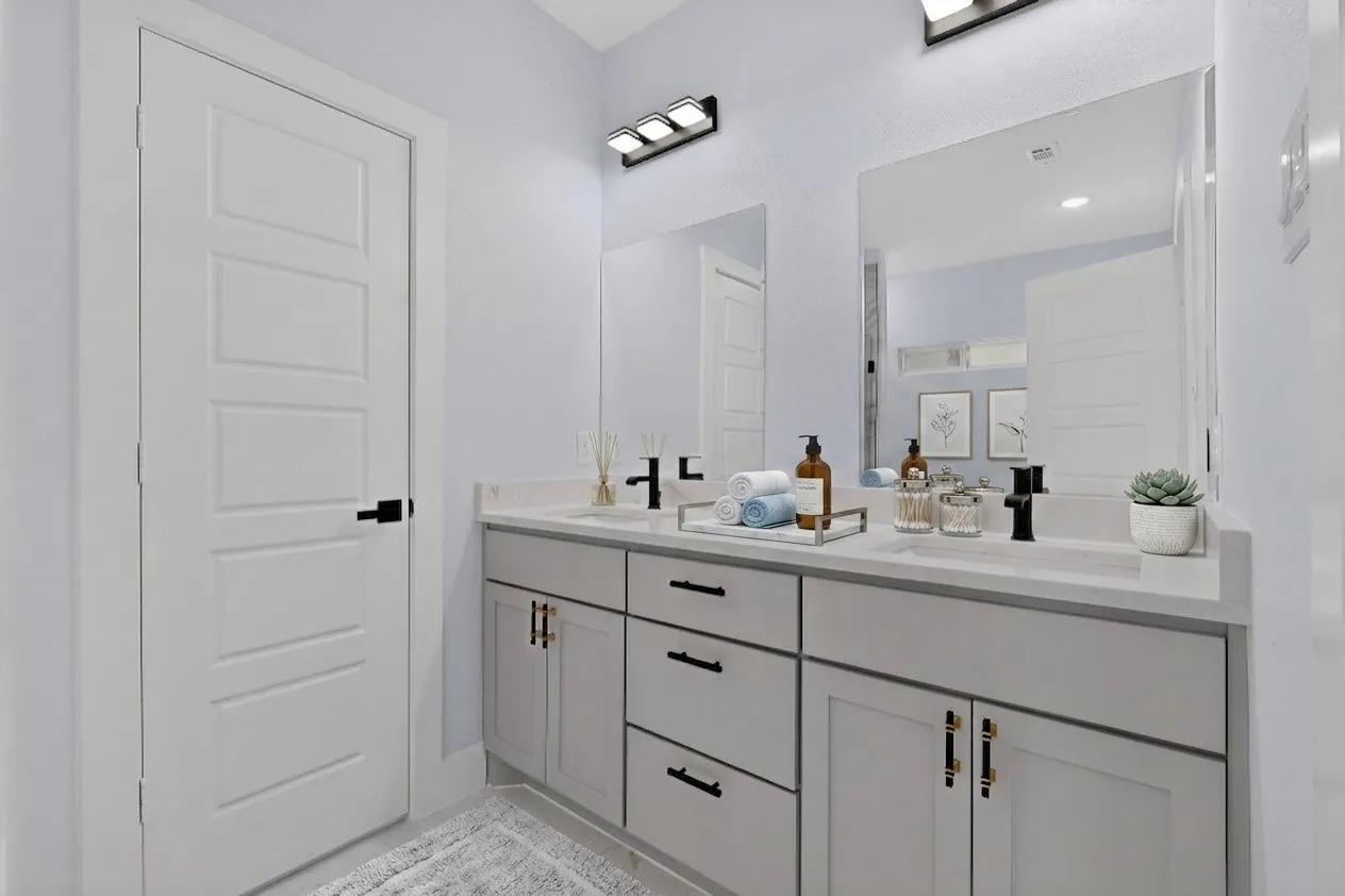 Dual vanity with light gray cabinetry, matte black hardware, and two integrated rectangular sinks
