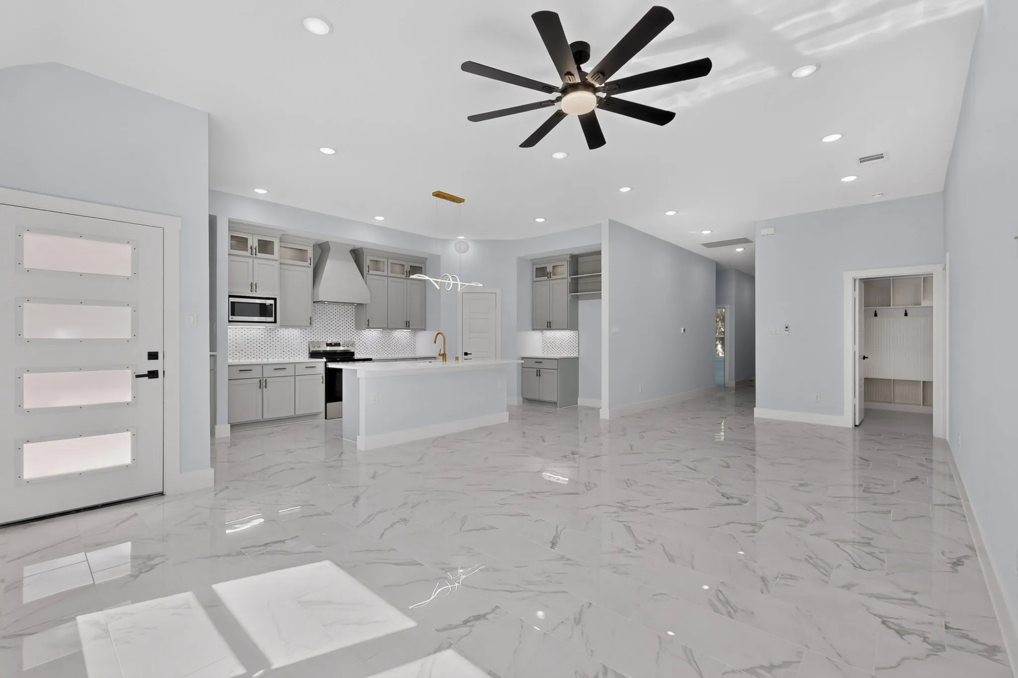 Spacious open-concept living area featuring large format tile flooring, recessed lighting, and a contemporary ceiling fan