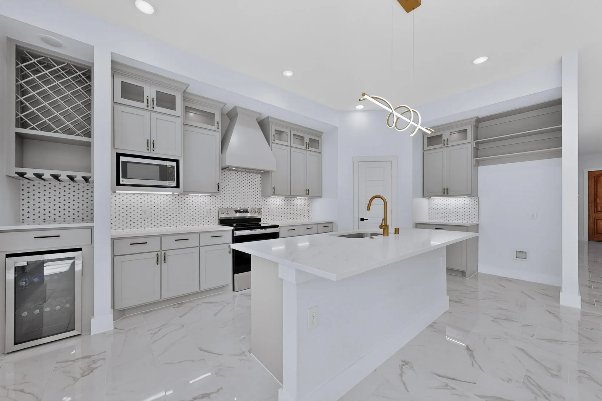 Kitchen featuring a central island with an integrated sink, light-toned cabinetry, stainless steel appliances, a geometric tile backsplash, and polished tile flooring