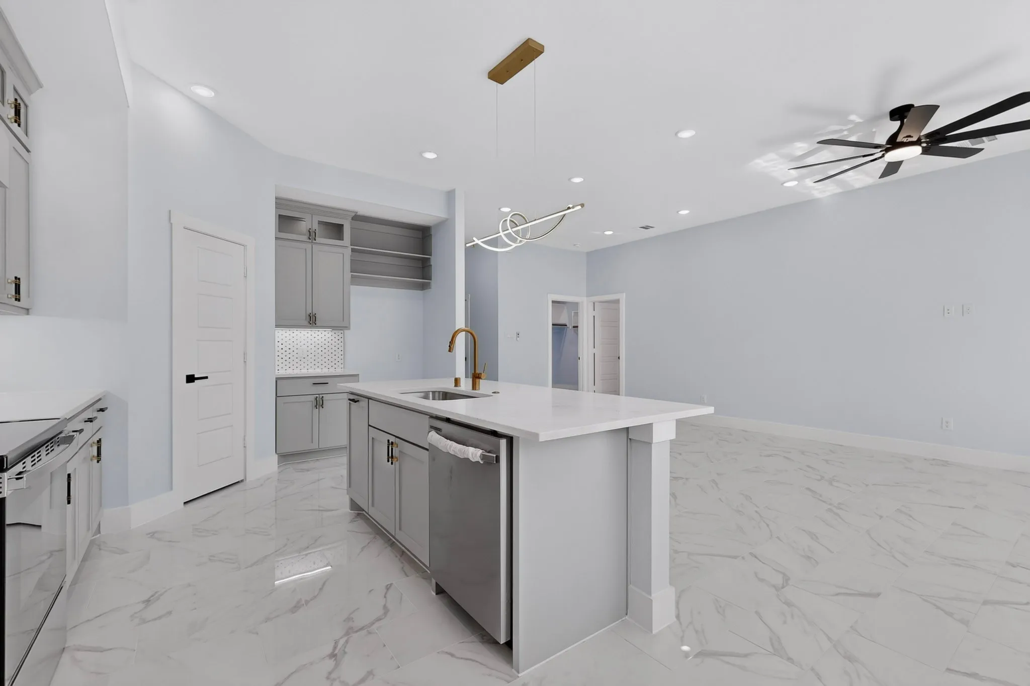 Kitchen featuring a center island with sink, stainless steel dishwasher, white countertops, and gray cabinetry