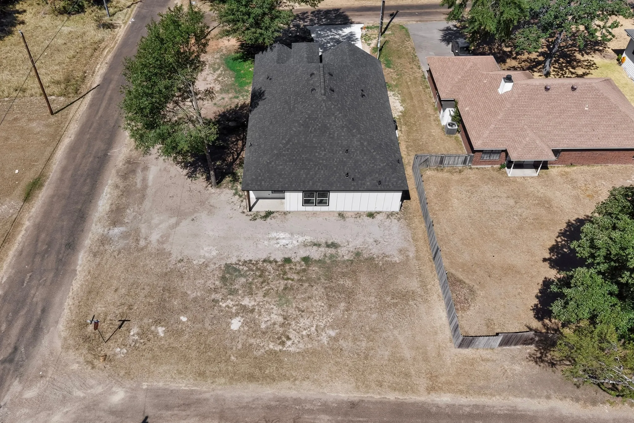 Newly constructed residence featuring a dark shingle roof and a spacious, undeveloped lot