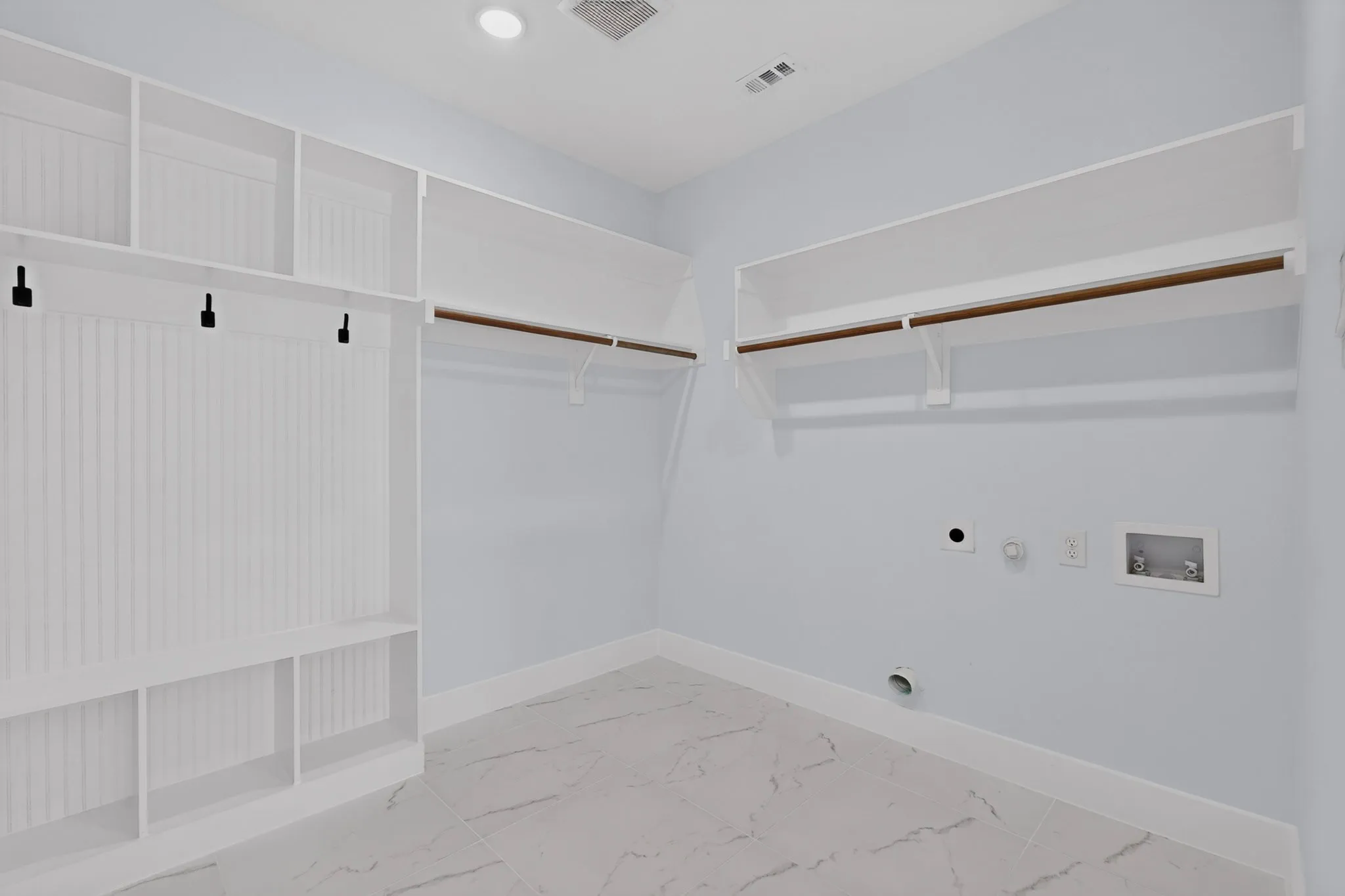 Utility room featuring built-in shelving, hanging rods, and tile flooring