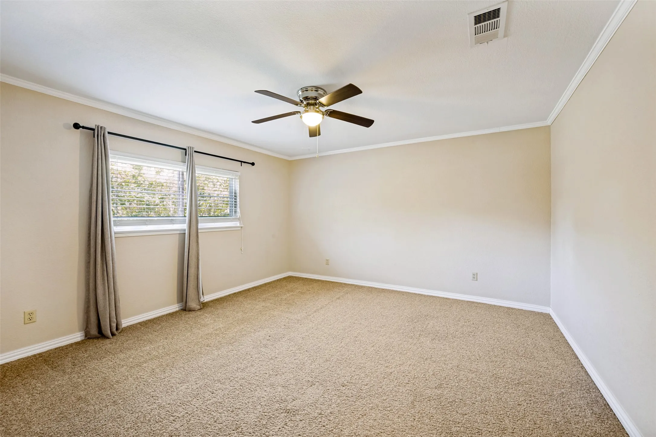 Spacious room featuring carpeting, crown molding, double windows with blinds, and a ceiling fan with integrated lighting