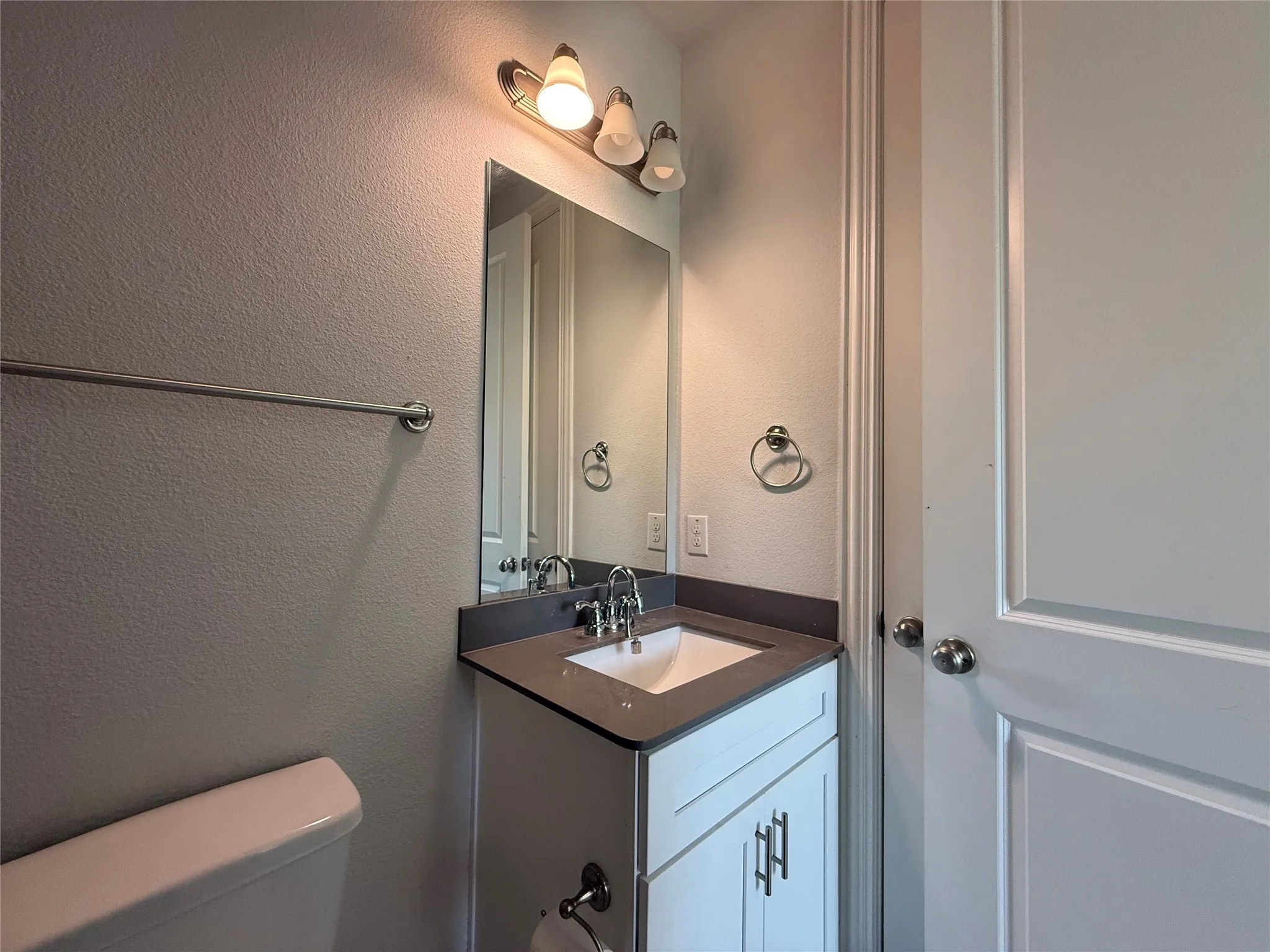 Vanity with dark countertop, undermount sink, and chrome faucet