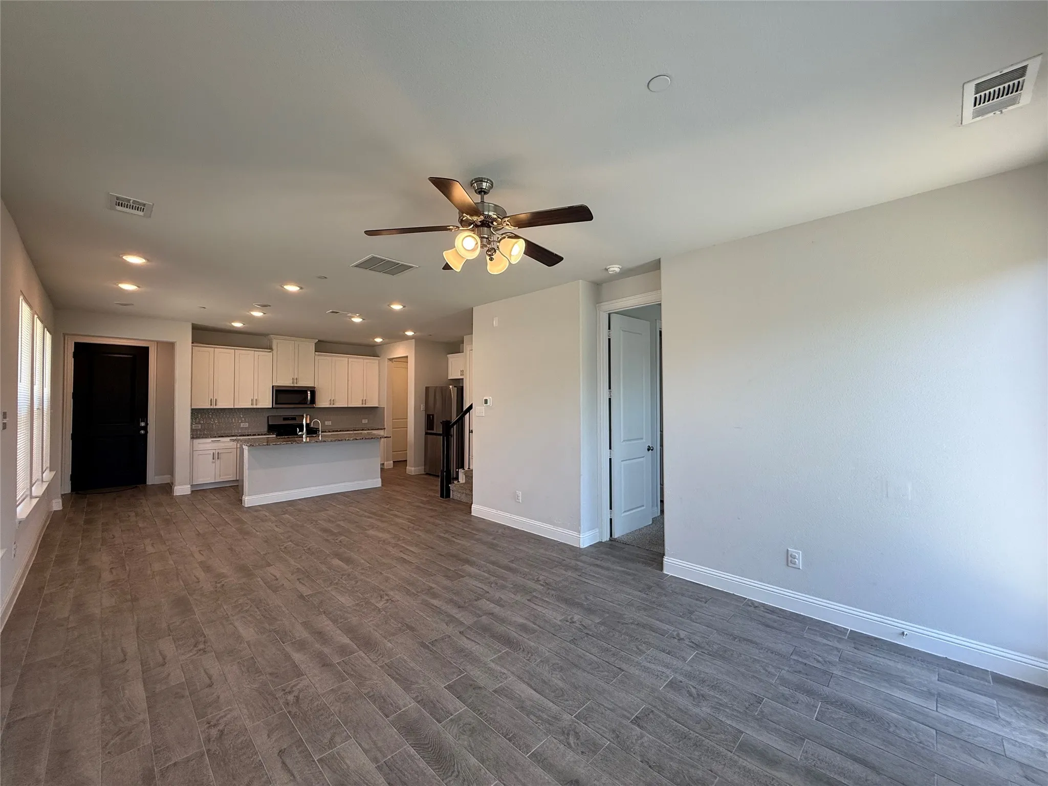 Open-concept living area featuring wood-finish flooring, recessed lighting, and a ceiling fan