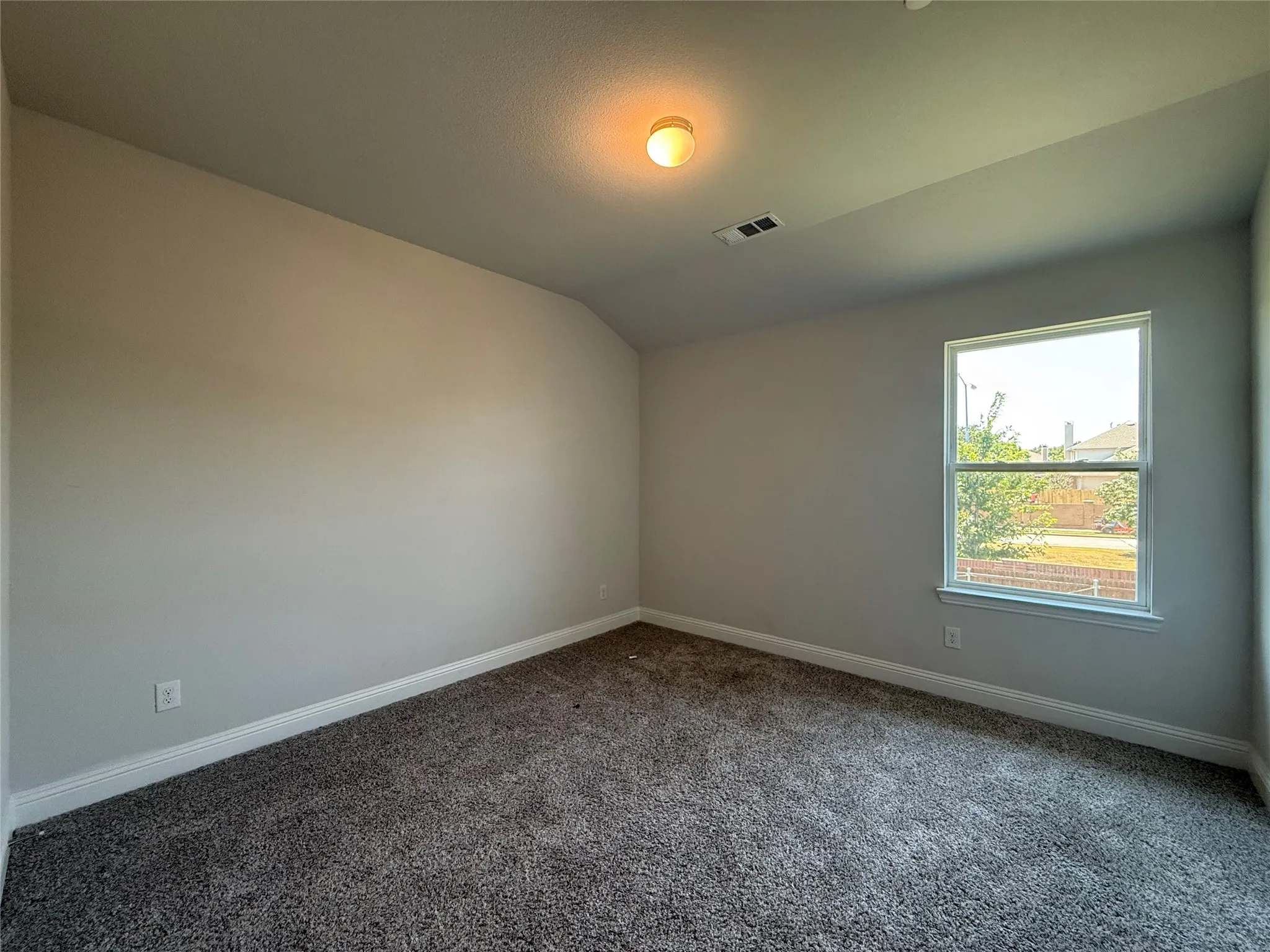 Neutral wall paint, textured carpet flooring, single window, and a ceiling-mounted light fixture
