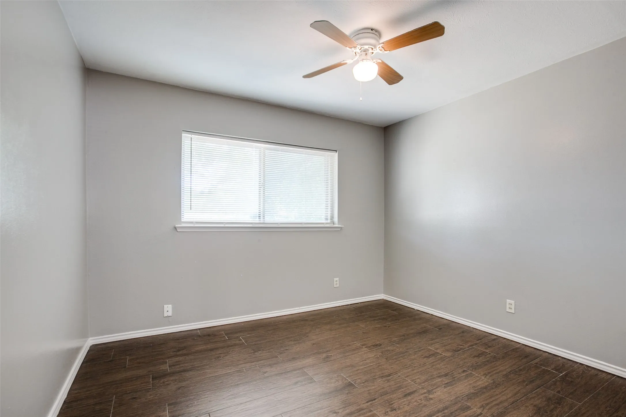 Neutral wall tones, wood-finish flooring, ceiling fan, and window with blinds
