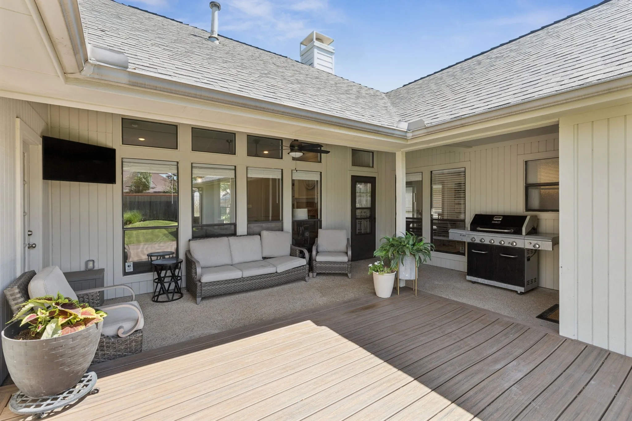 Covered patio with a wood-finish deck and textured concrete flooring