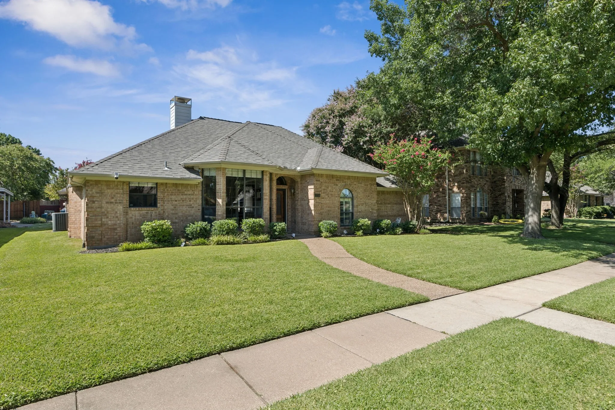 Brick exterior featuring a gabled roof, prominent bay windows, and a dedicated walkway leading to the entry