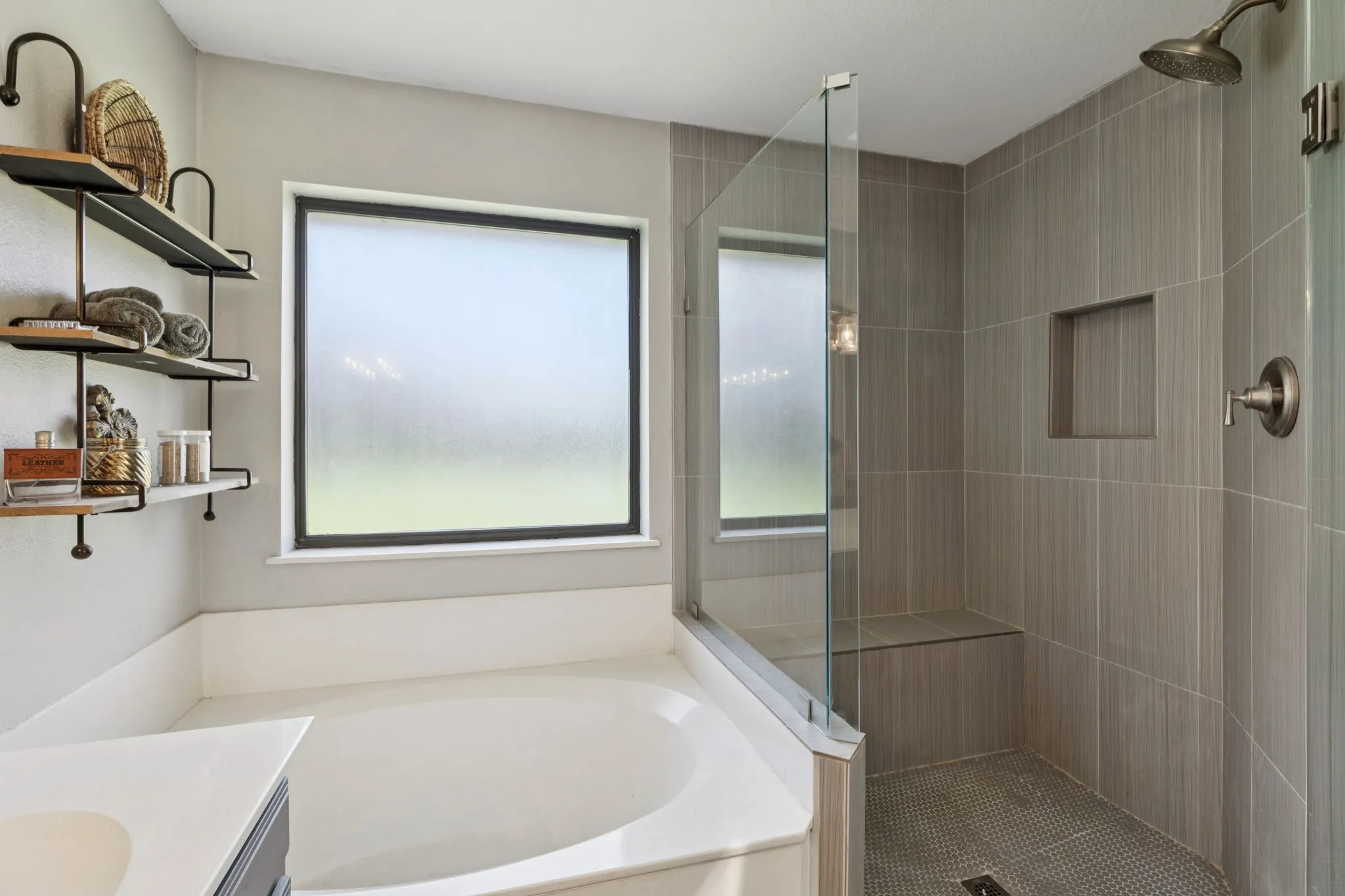 Soaking tub with a frosted window, walk-in shower with a built-in bench, and floor-to-ceiling tile