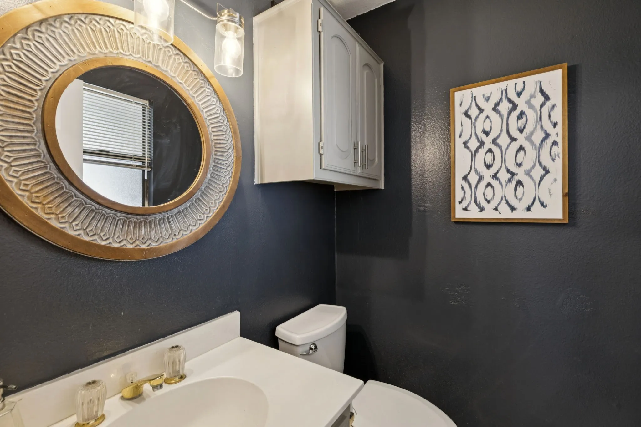 Vanity with an integrated sink, gold-tone faucet, and clear acrylic handles