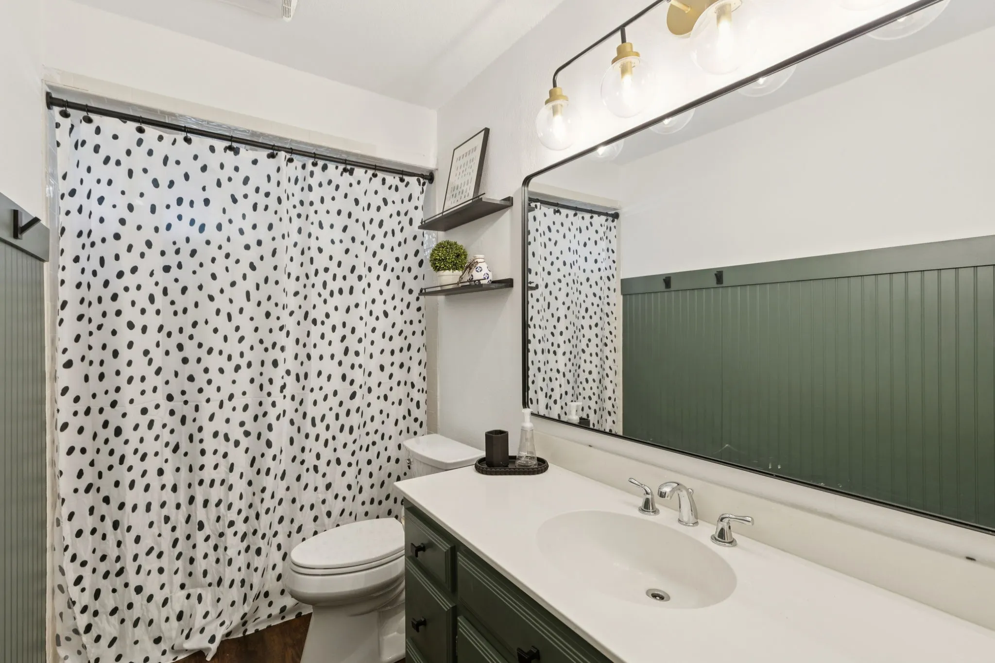 Vanity with an integrated white sink, chrome faucet, and dark green cabinetry