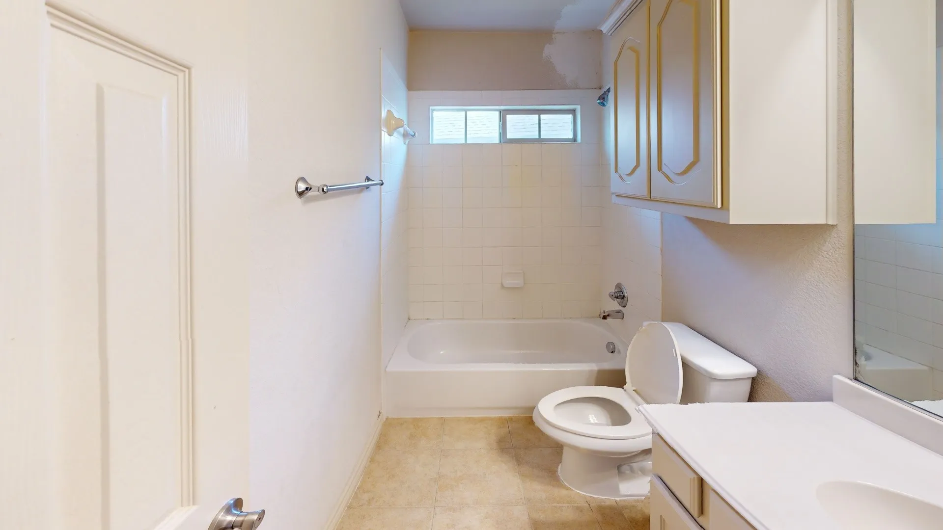 Built-in bathtub with shower, white tile surround, and privacy window