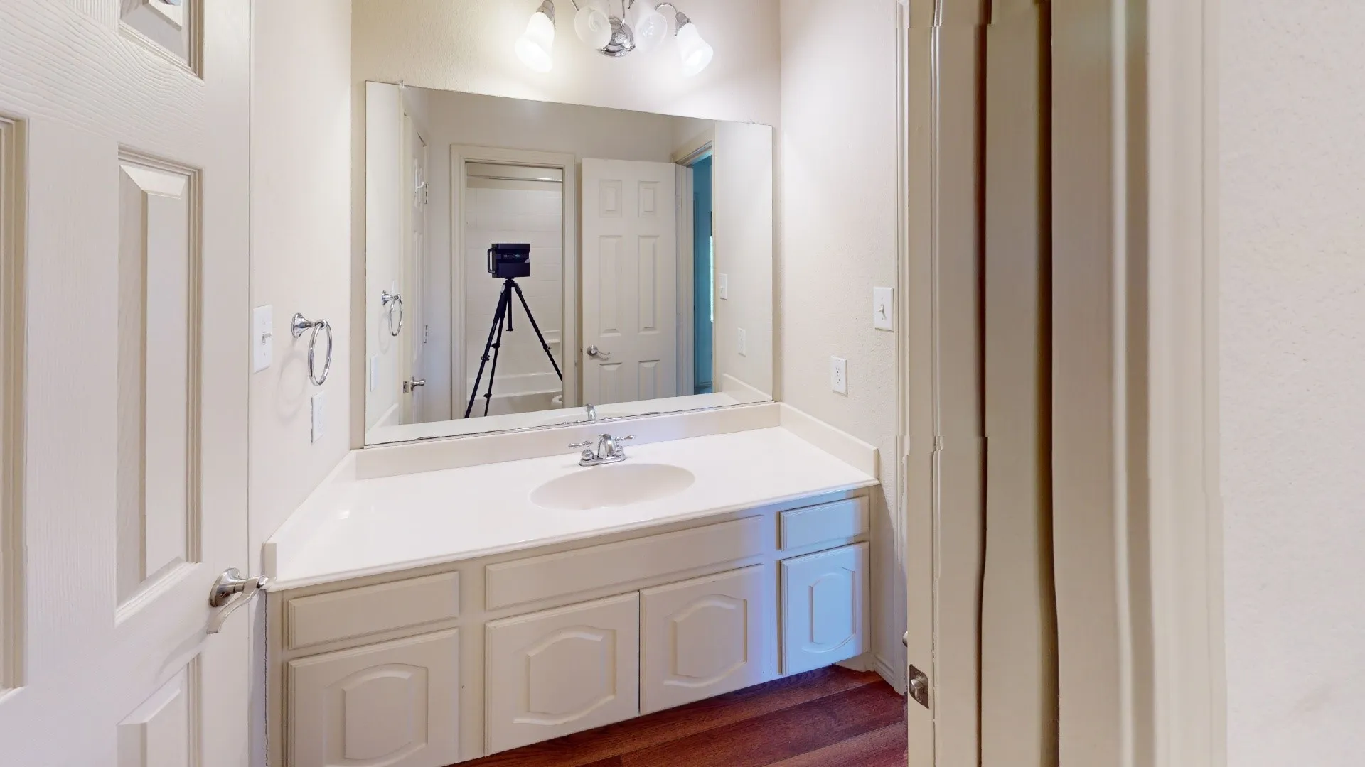 White vanity with integrated sink, chrome faucet, and expansive wall-mounted mirror