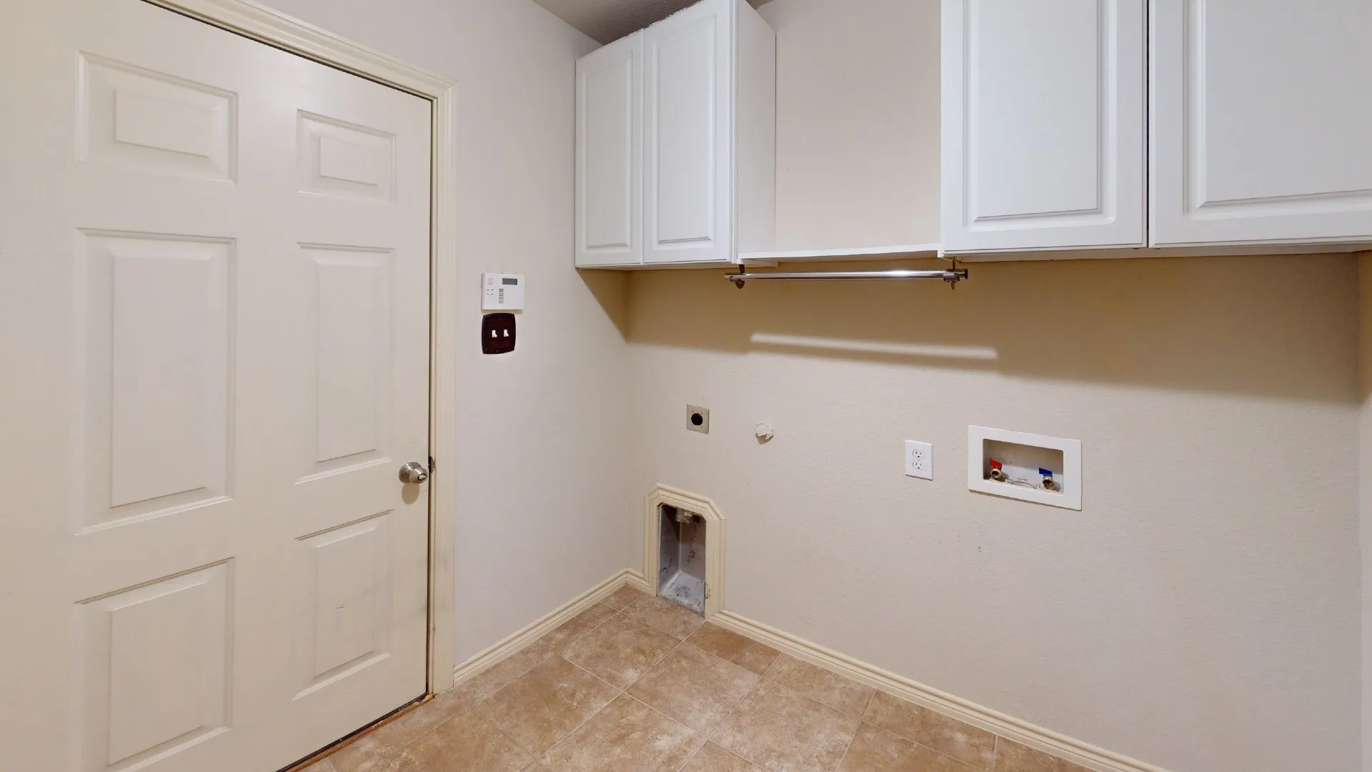 Utility area featuring upper cabinetry, a hanging rod, and tile flooring