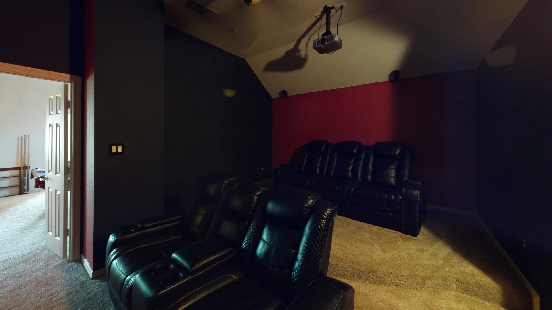 Carpeted media room featuring a mounted projector and a tiered floor