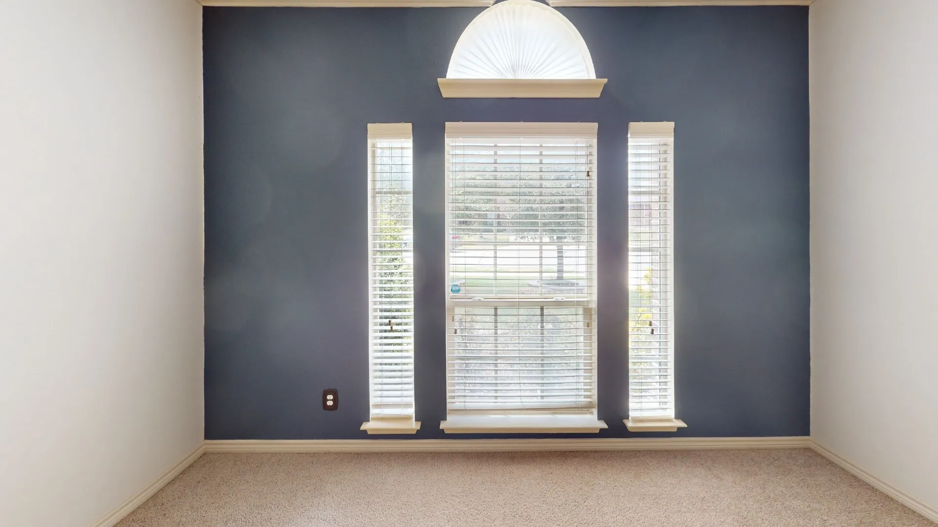 Carpeted room featuring a dark accent wall, white painted walls, white window trim, and a decorative arched window accent