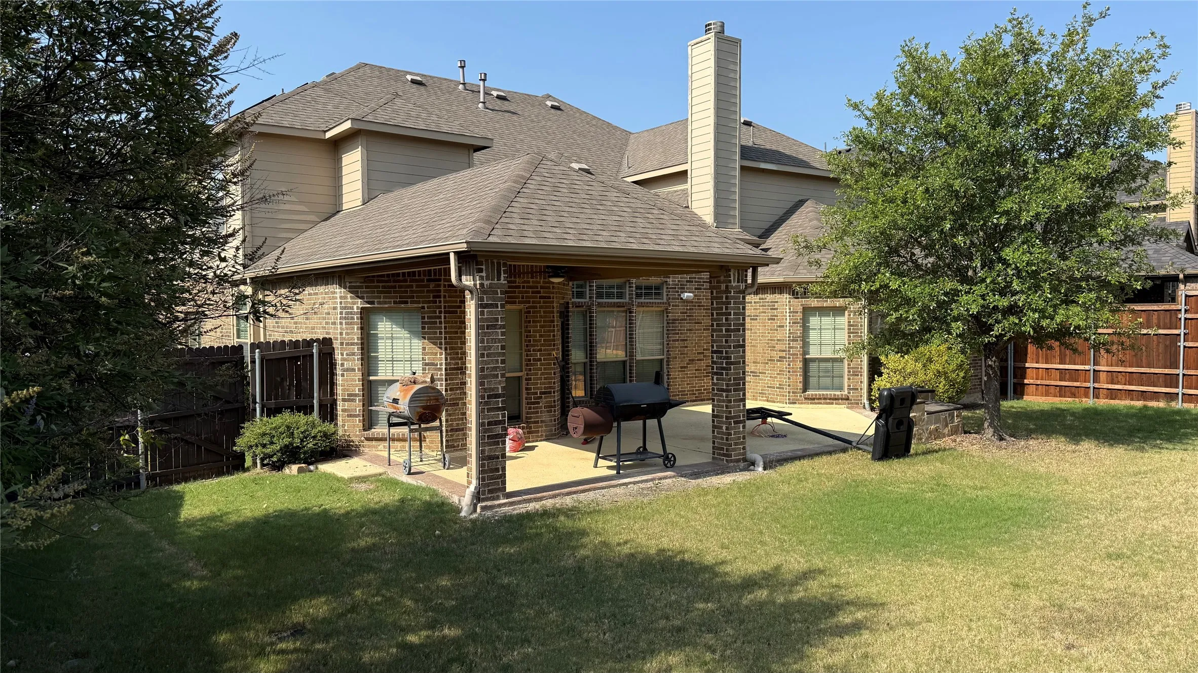 Brick exterior construction with a covered patio, concrete patio surface, and a fenced yard