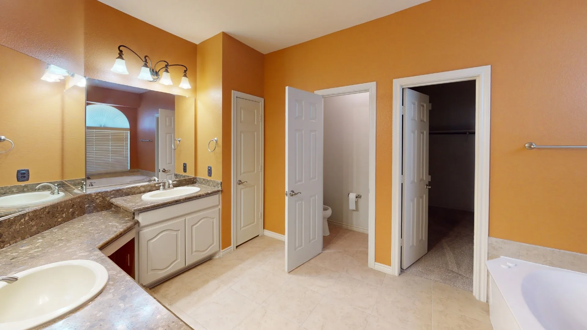 Dual vanity with undermount sinks, integrated countertop, built-in cabinetry, large mirror, and tiled flooring