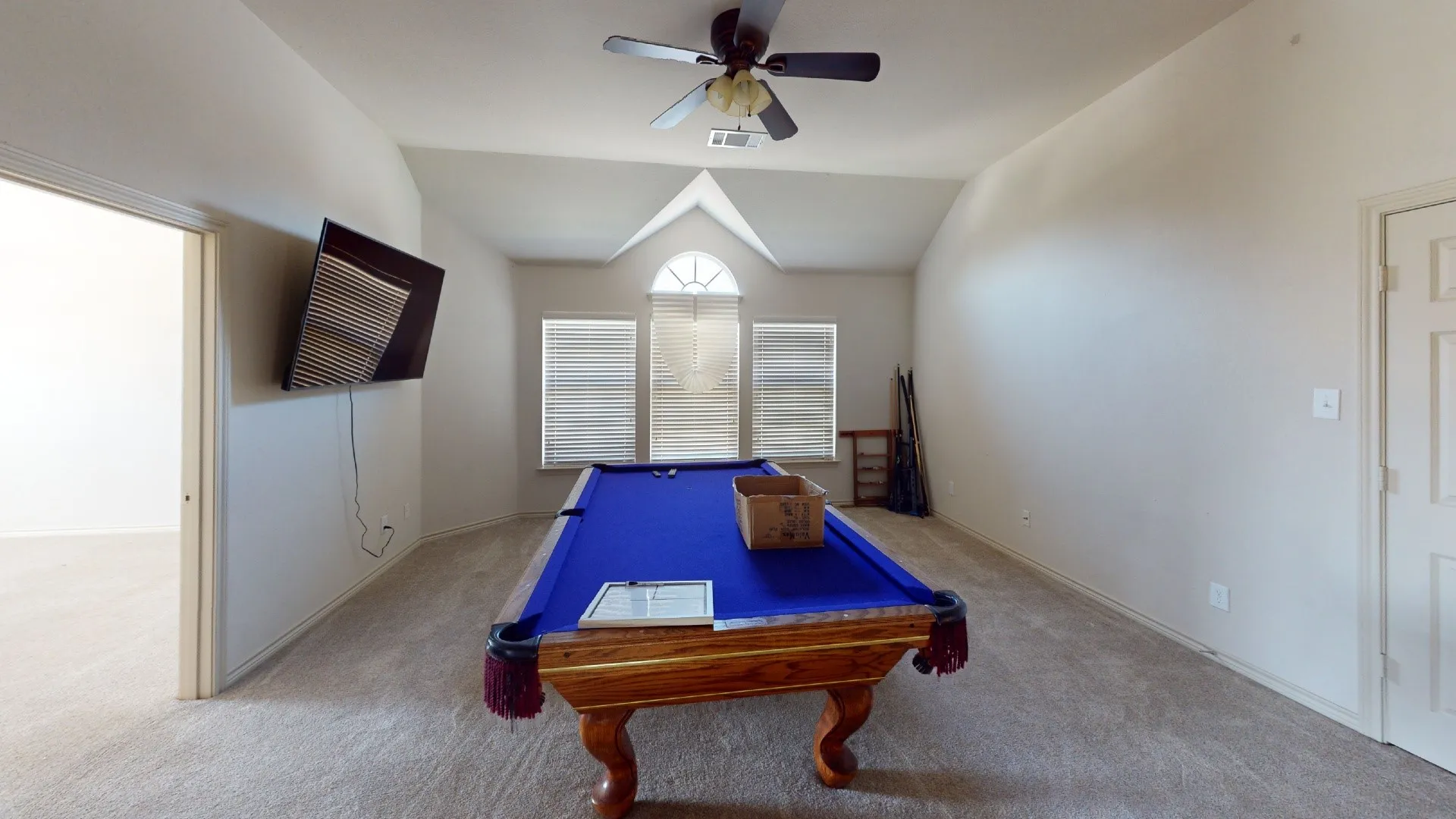 Vaulted ceiling featuring a ceiling fan, arched window with horizontal blinds, and carpeted flooring