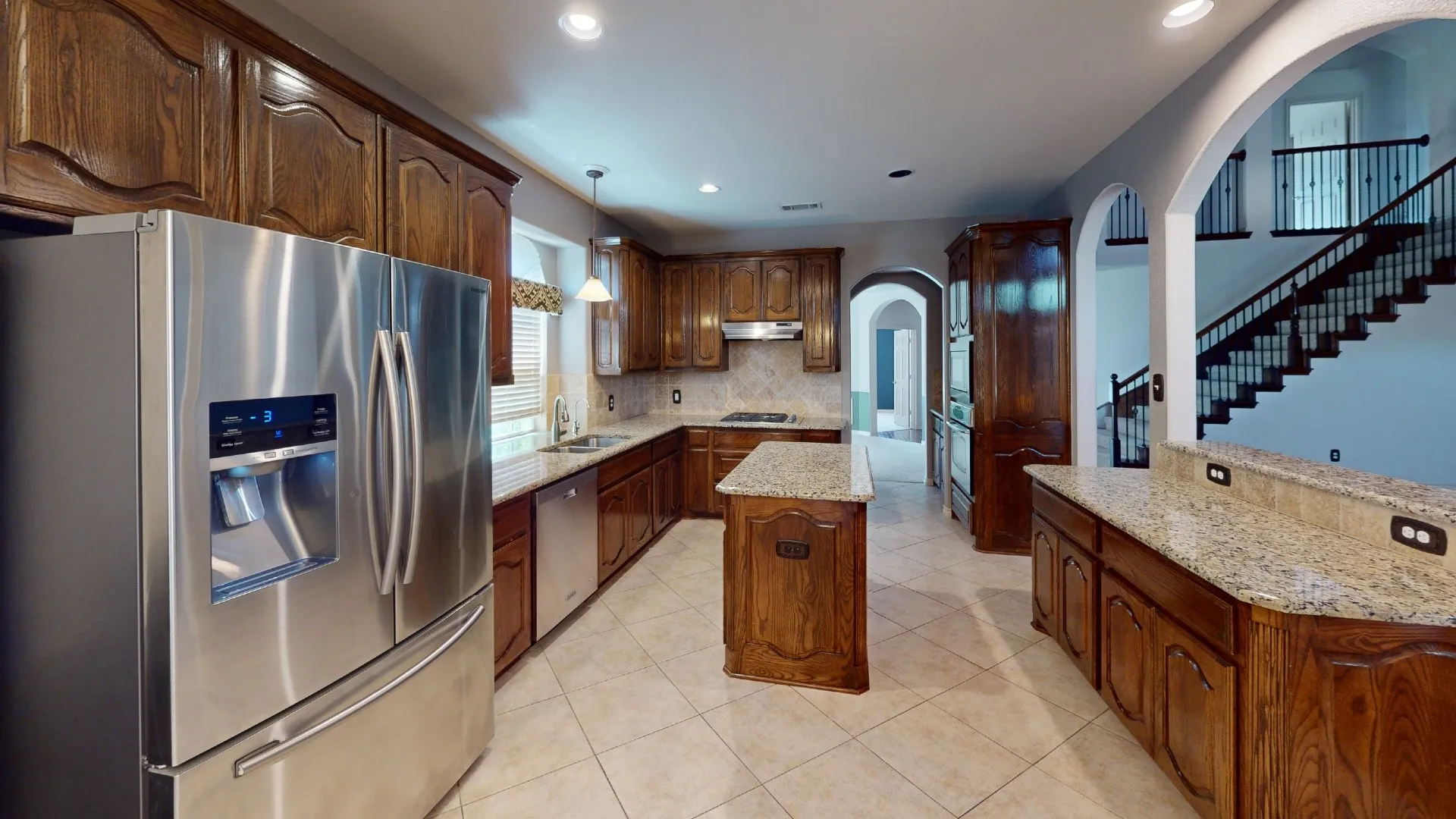 Kitchen featuring wood cabinetry, stainless steel appliances, a tiled backsplash, granite countertops, and a center island
