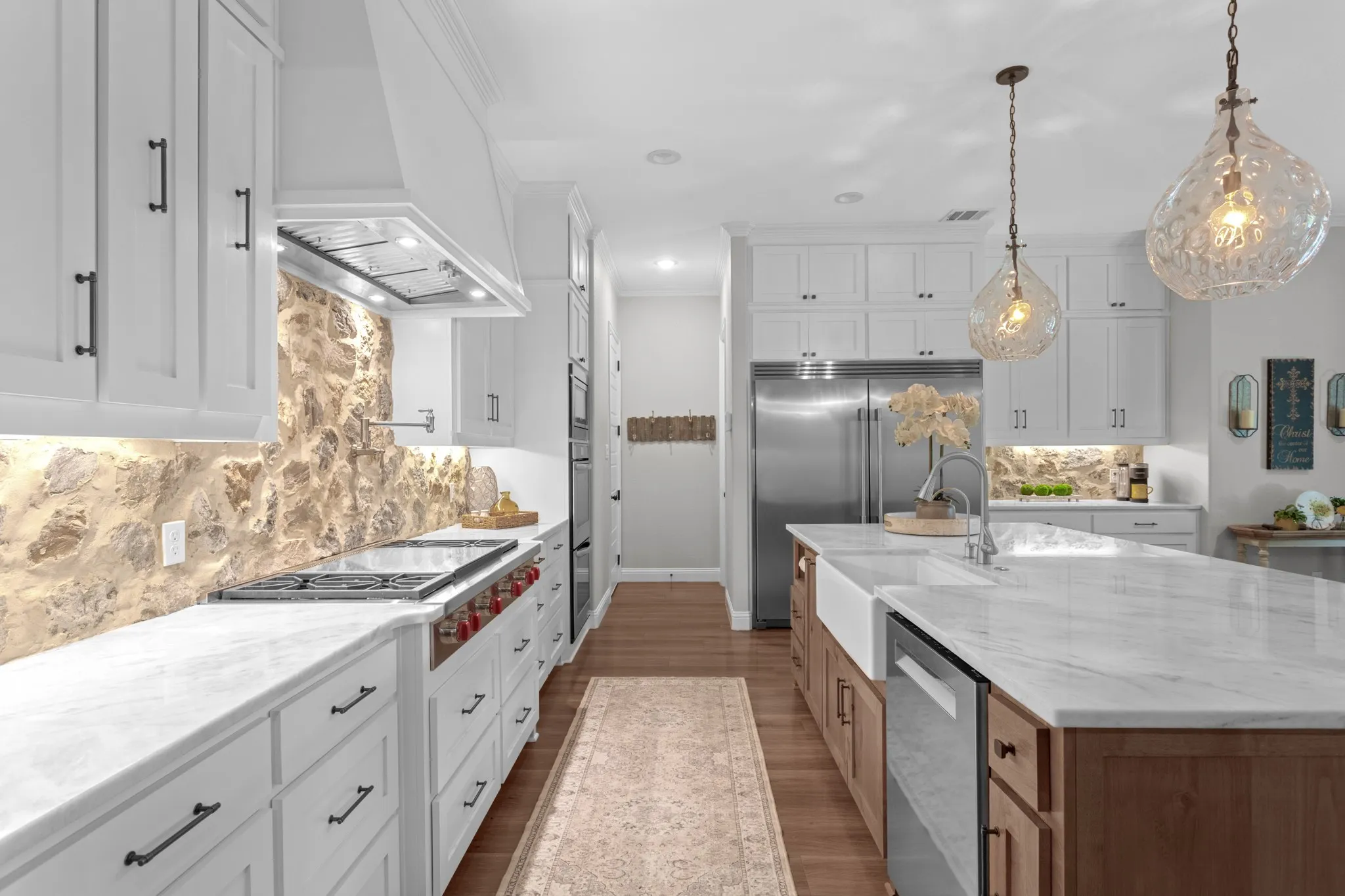 The spectacular kitchen features floor-to-ceiling cabinetry, an oversized island, butlers & walk in pantry, special-order quartz countertops, real-cut stone backsplash, farmhouse sink, commercial-style faucet, pot filler, double convection ovens & premium appliances.