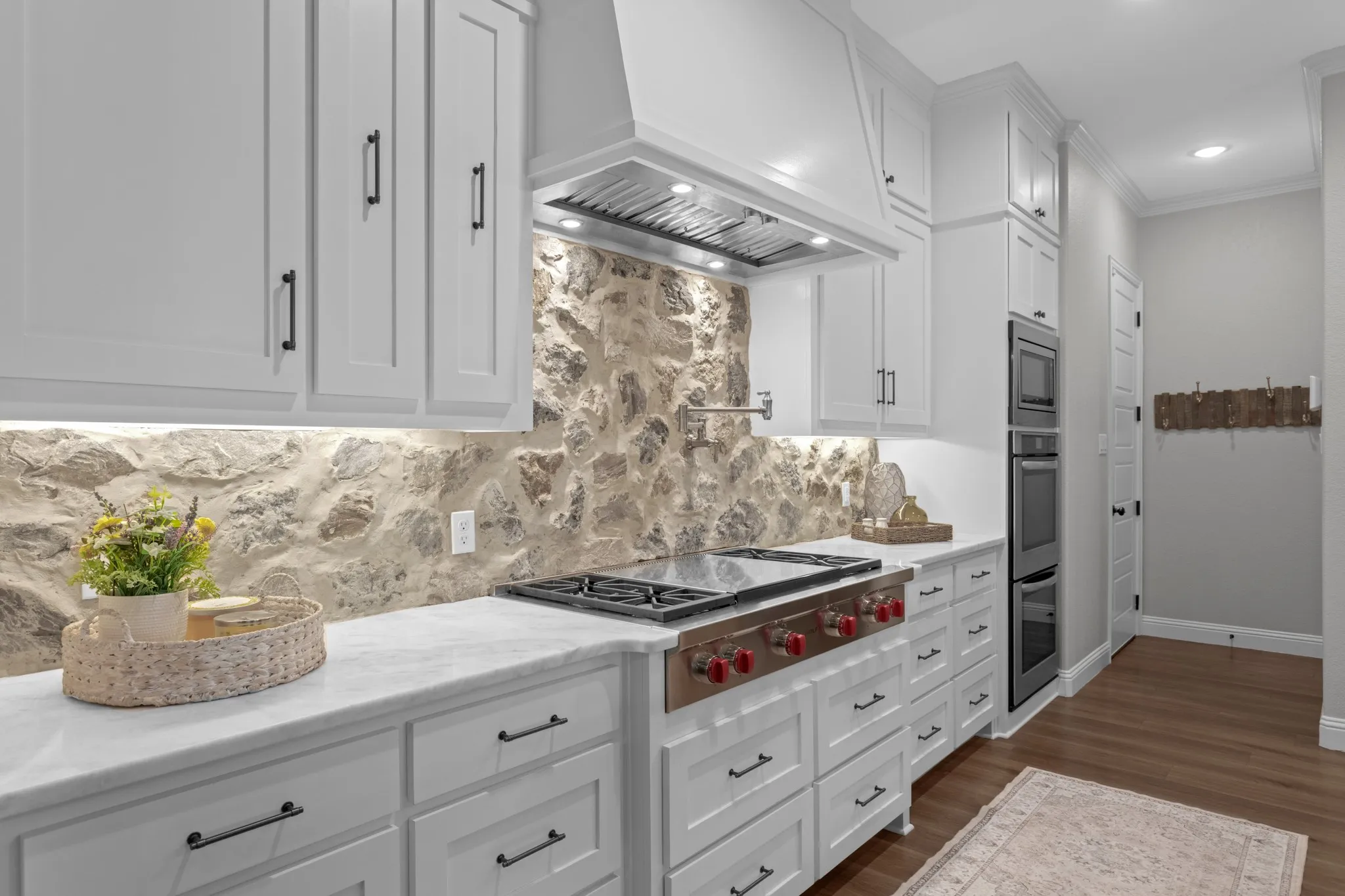 The spectacular kitchen features floor-to-ceiling cabinetry, an oversized island, butlers & walk in pantry, special-order quartz countertops, real-cut stone backsplash, farmhouse sink, commercial-style faucet, pot filler, double convection ovens & premium appliances.