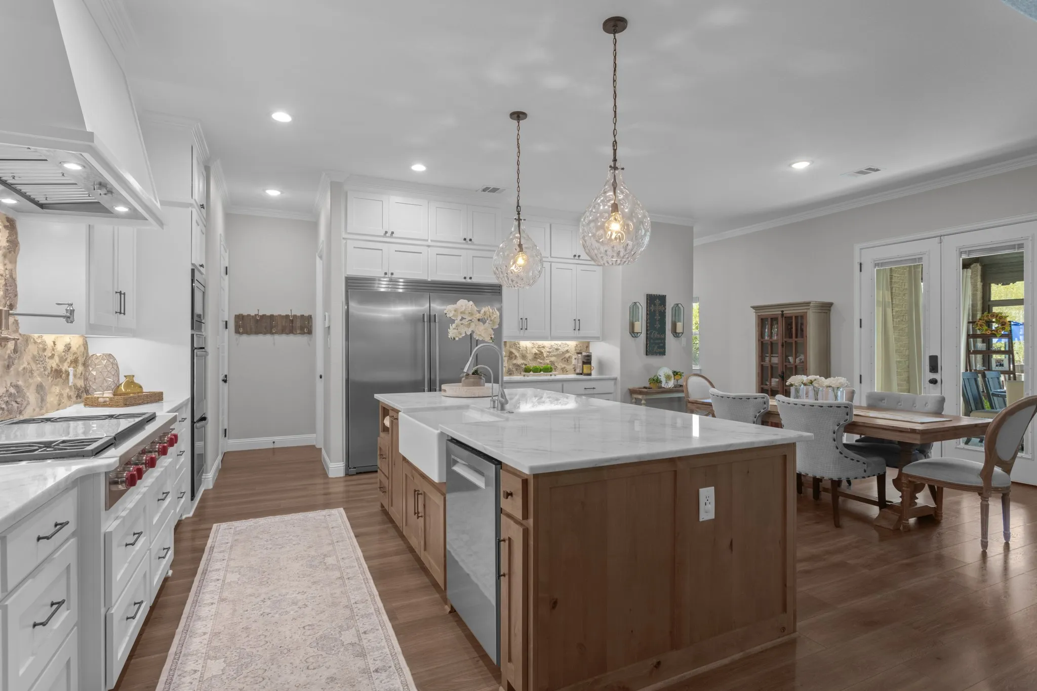 The spectacular kitchen features floor-to-ceiling cabinetry, an oversized island, butlers & walk in pantry, special-order quartz countertops, real-cut stone backsplash, farmhouse sink, commercial-style faucet, pot filler, double convection ovens & premium appliances.