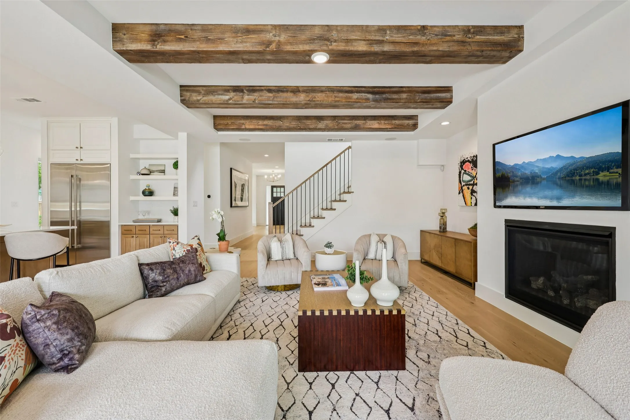 Living area featuring exposed wood beams, hardwood flooring, a built-in fireplace, and a staircase with metal railings