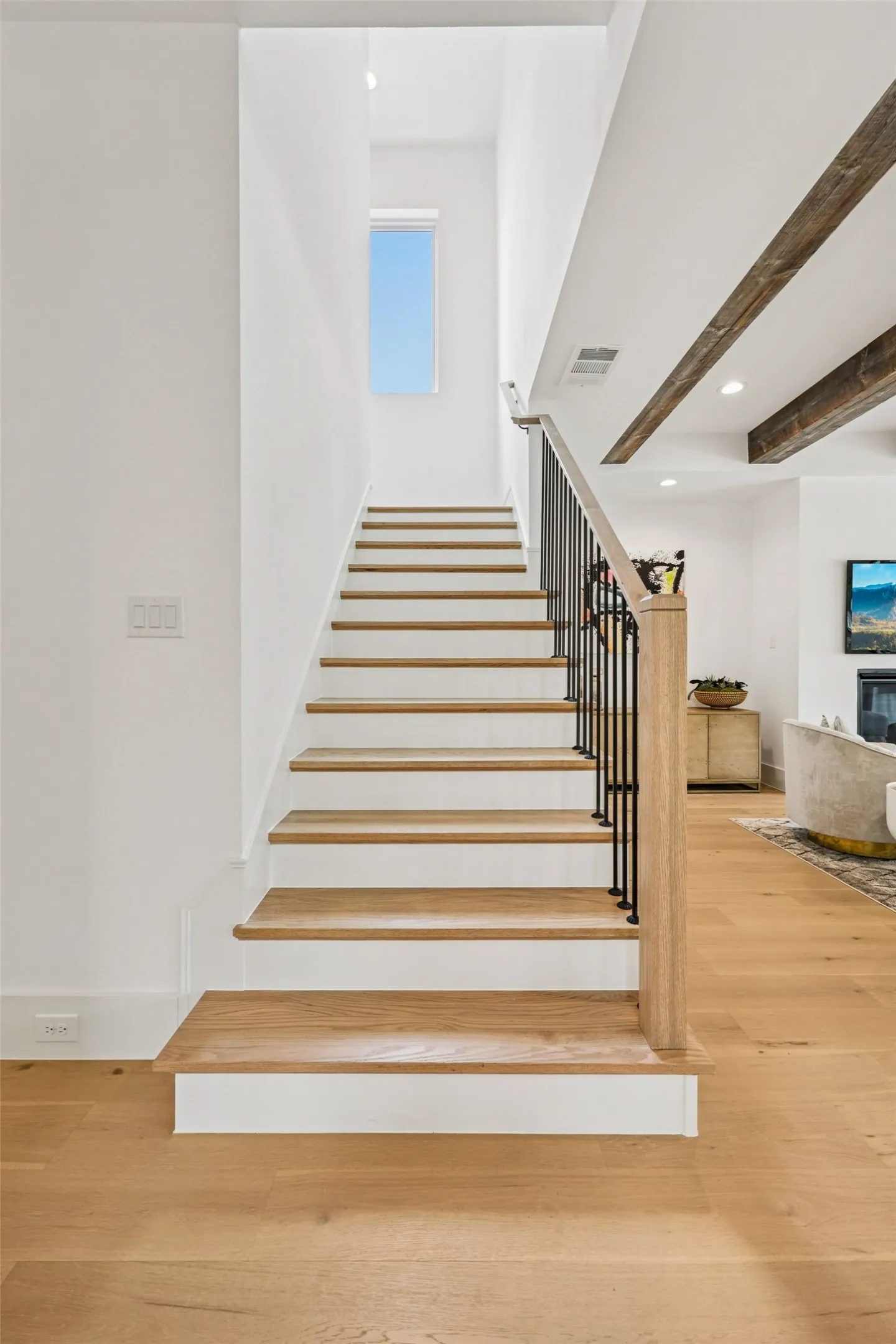Hardwood stairs with wrought iron balusters, natural wood handrail, and high ceilings