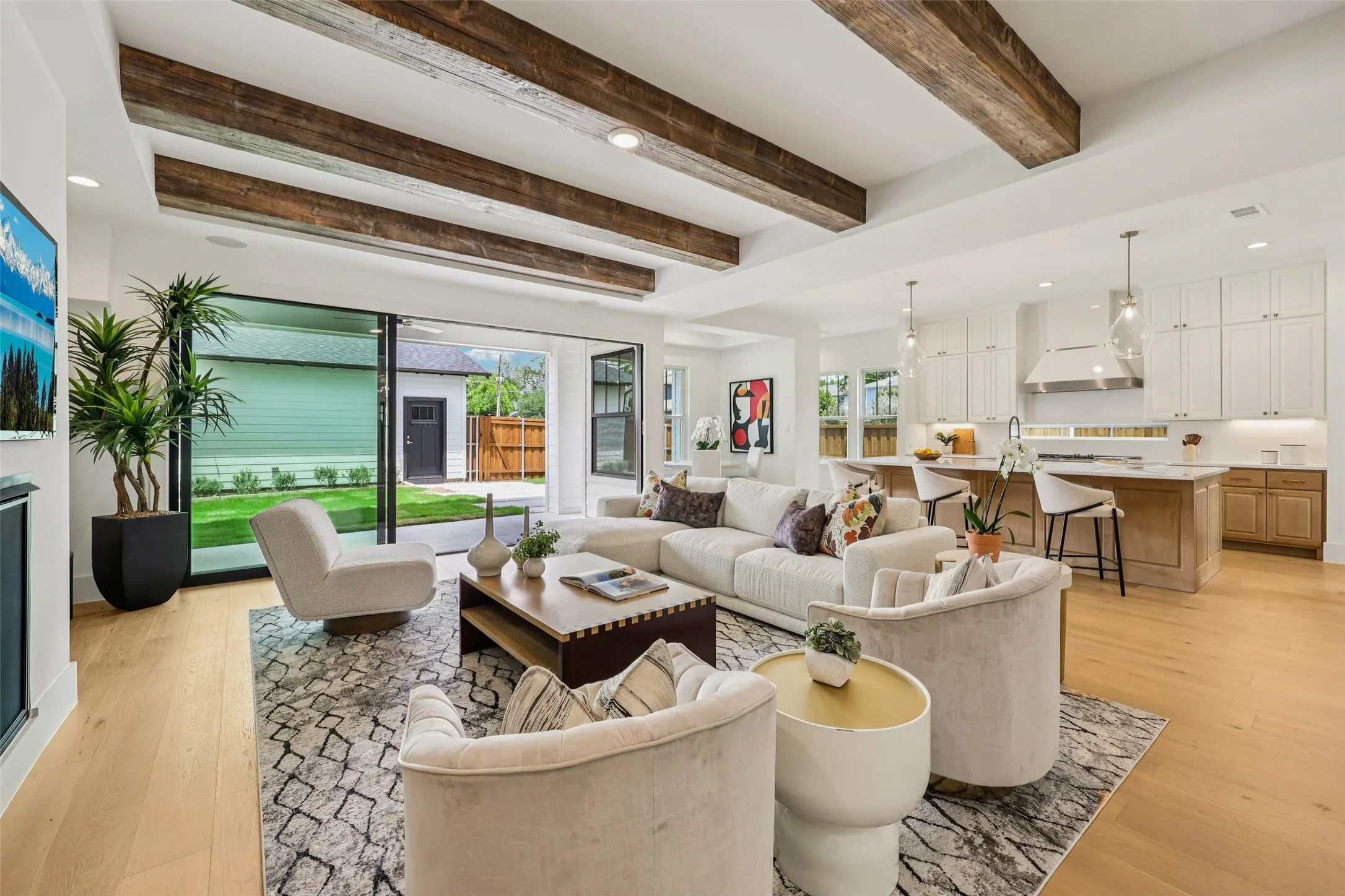 Open concept living space with wood-finish flooring, exposed ceiling beams, and recessed lighting