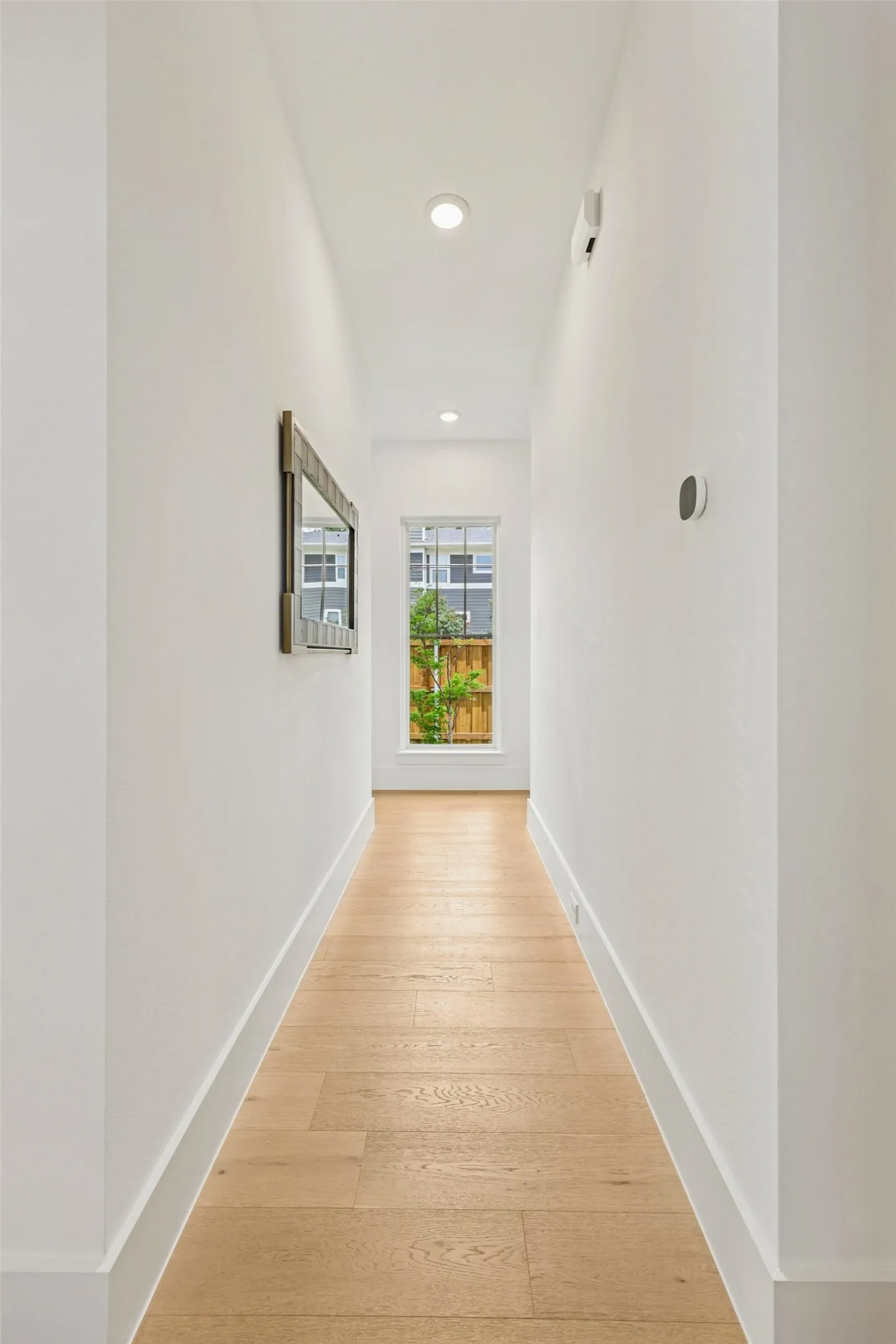 Recessed lighting, wood-finish flooring, white walls, and a window