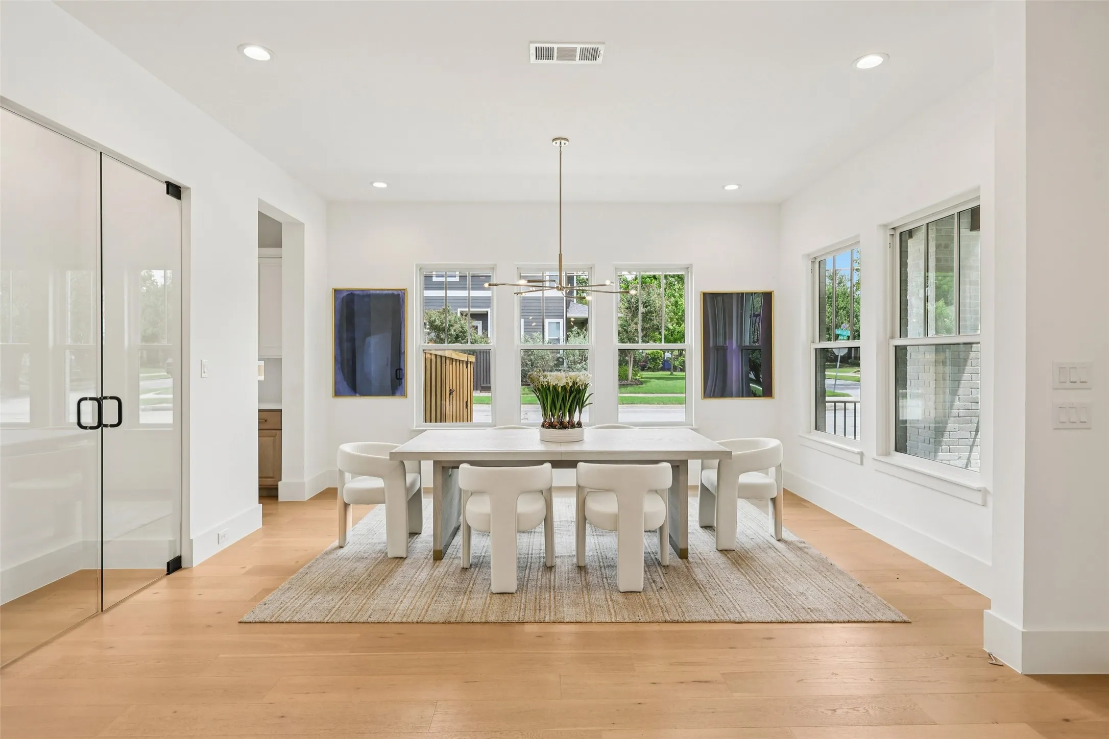 Recessed lighting, wood-finish flooring, multiple windows, and a modern linear chandelier
