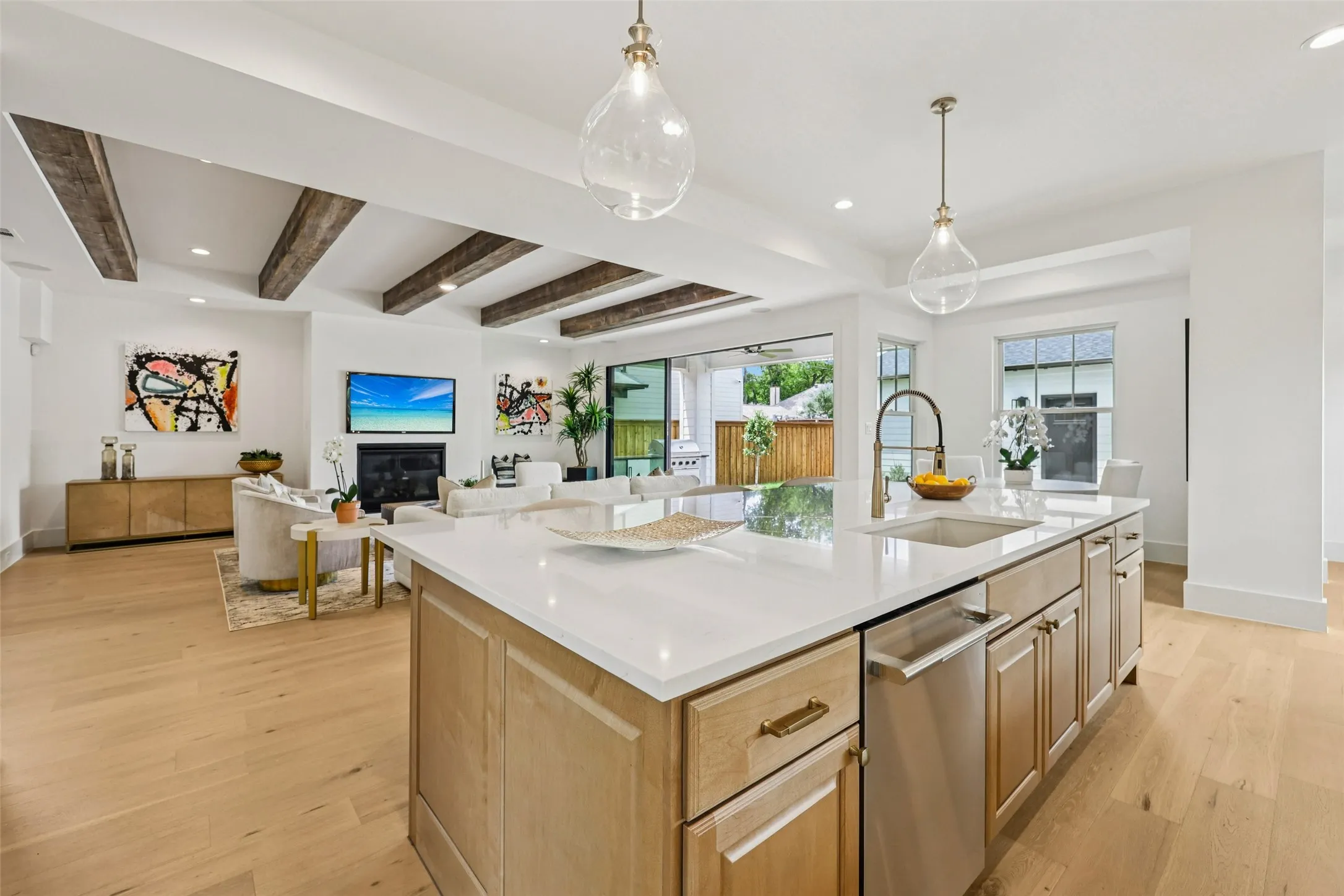 Gourmet kitchen island with an undermount sink, two pendant light fixtures, and a dishwasher