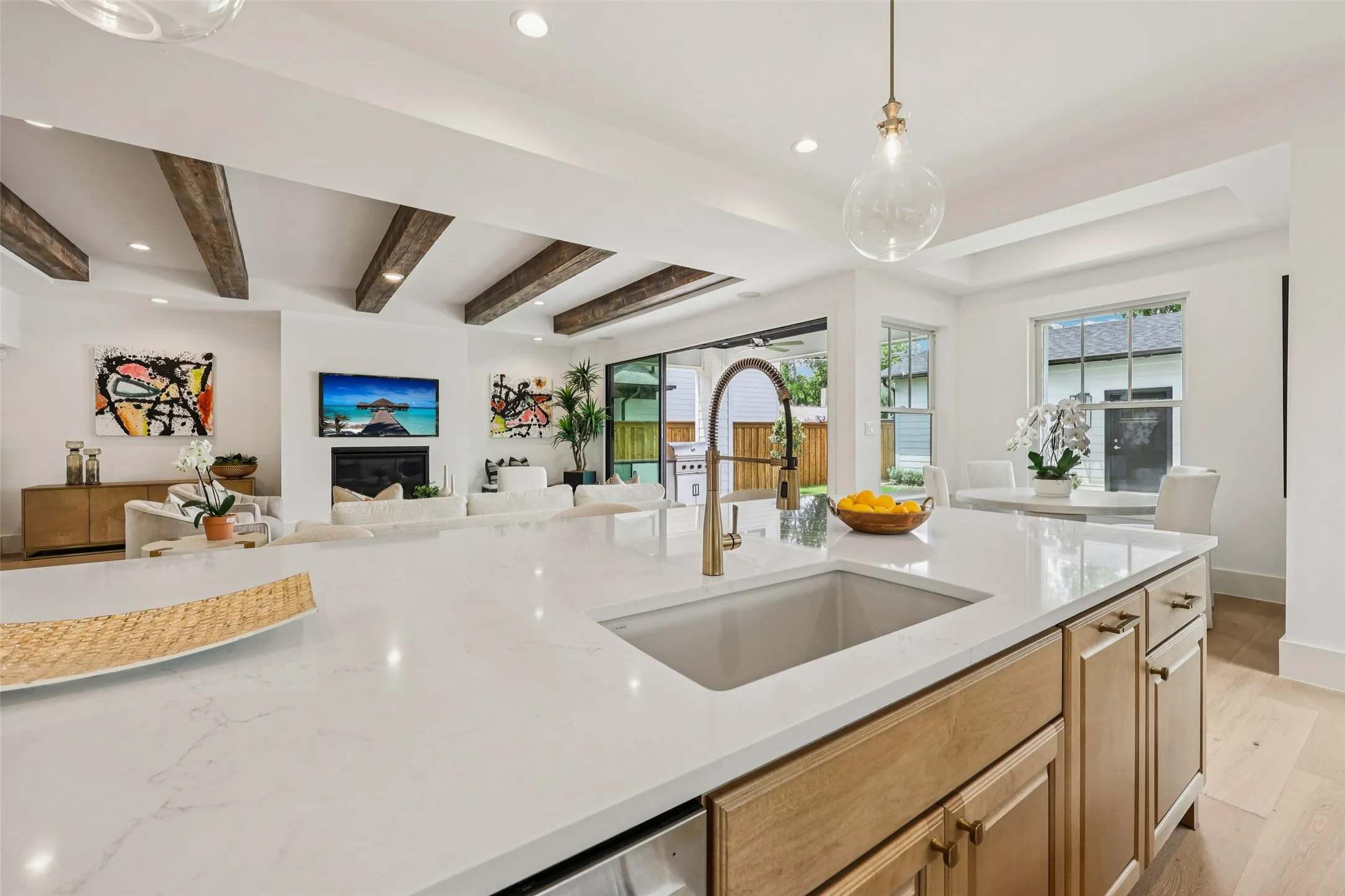 Spacious kitchen island with a single-basin sink and a gold-tone faucet, complemented by light wood-finish cabinetry