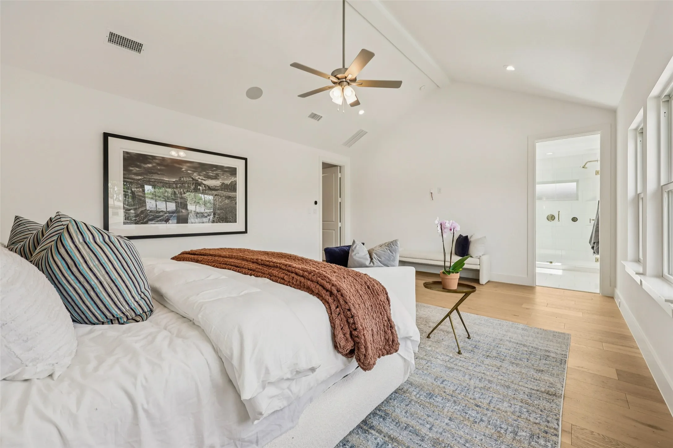 Vaulted ceiling with exposed beam, wood-finish flooring, ceiling fan with integrated lighting, recessed lighting, multiple windows