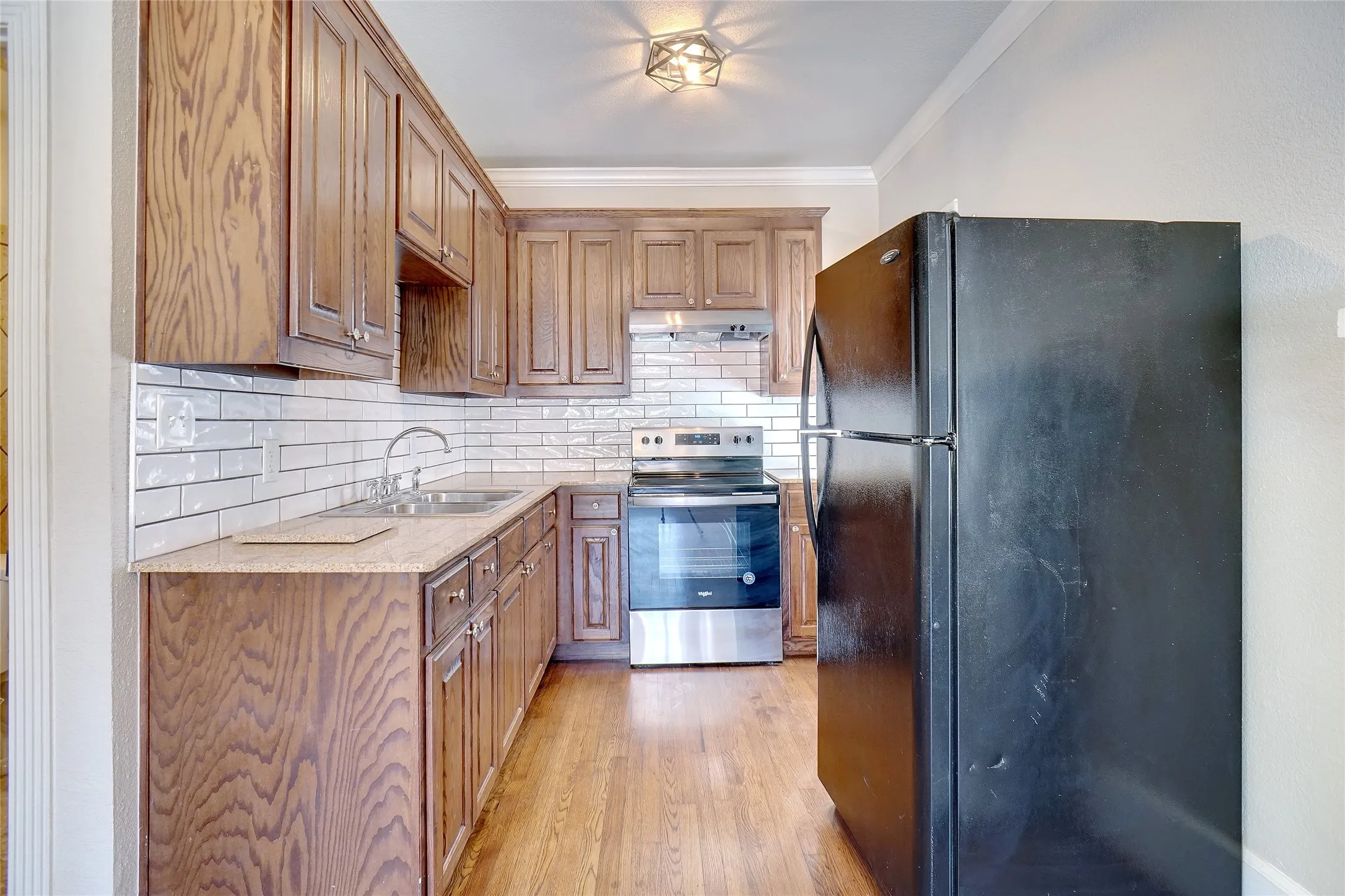 Kitchen featuring wood-finish cabinetry, subway tile backsplash, and wood-finish flooring