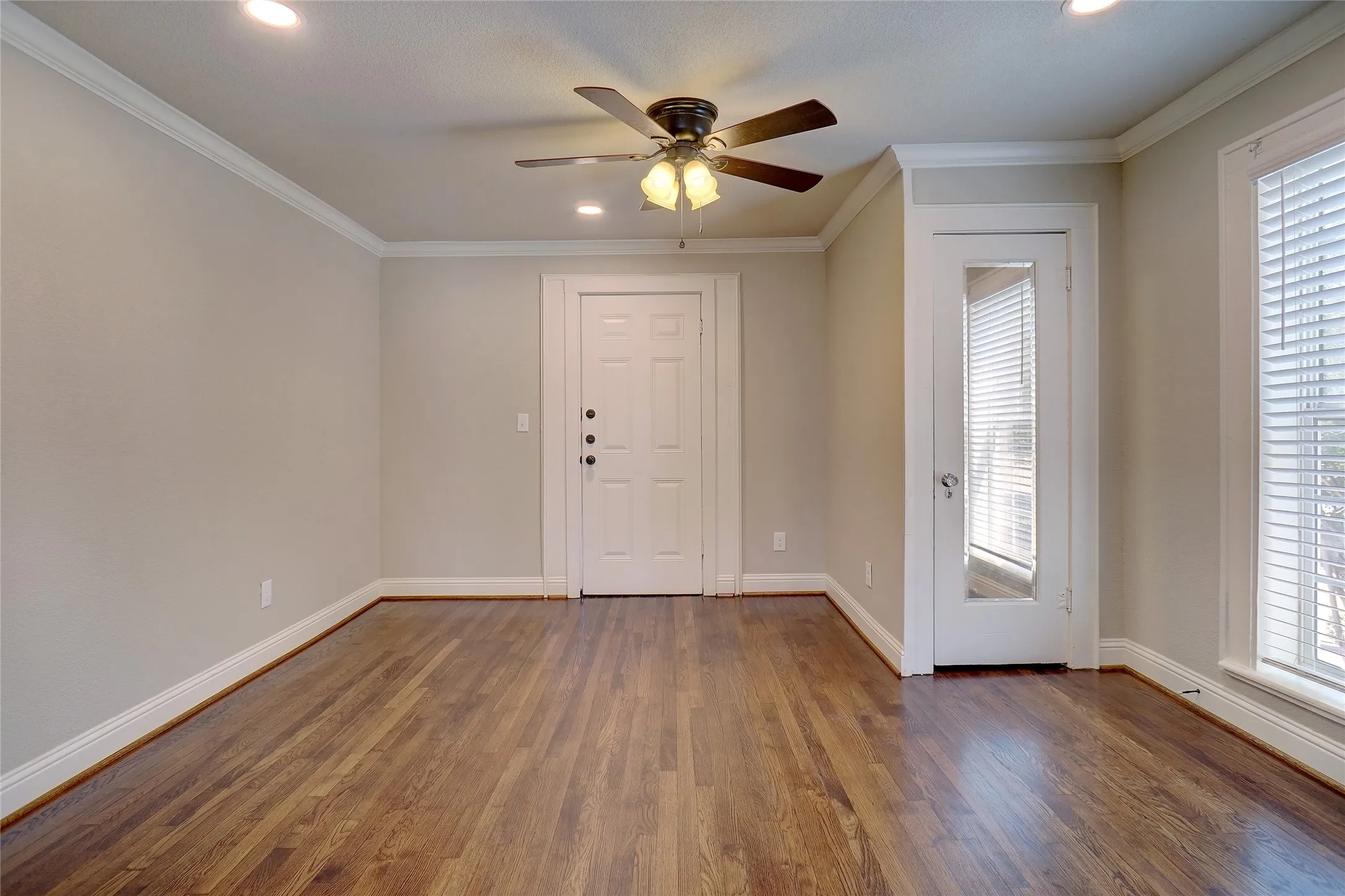 Hardwood flooring, crown molding, recessed lighting, ceiling fan, and white trim throughout